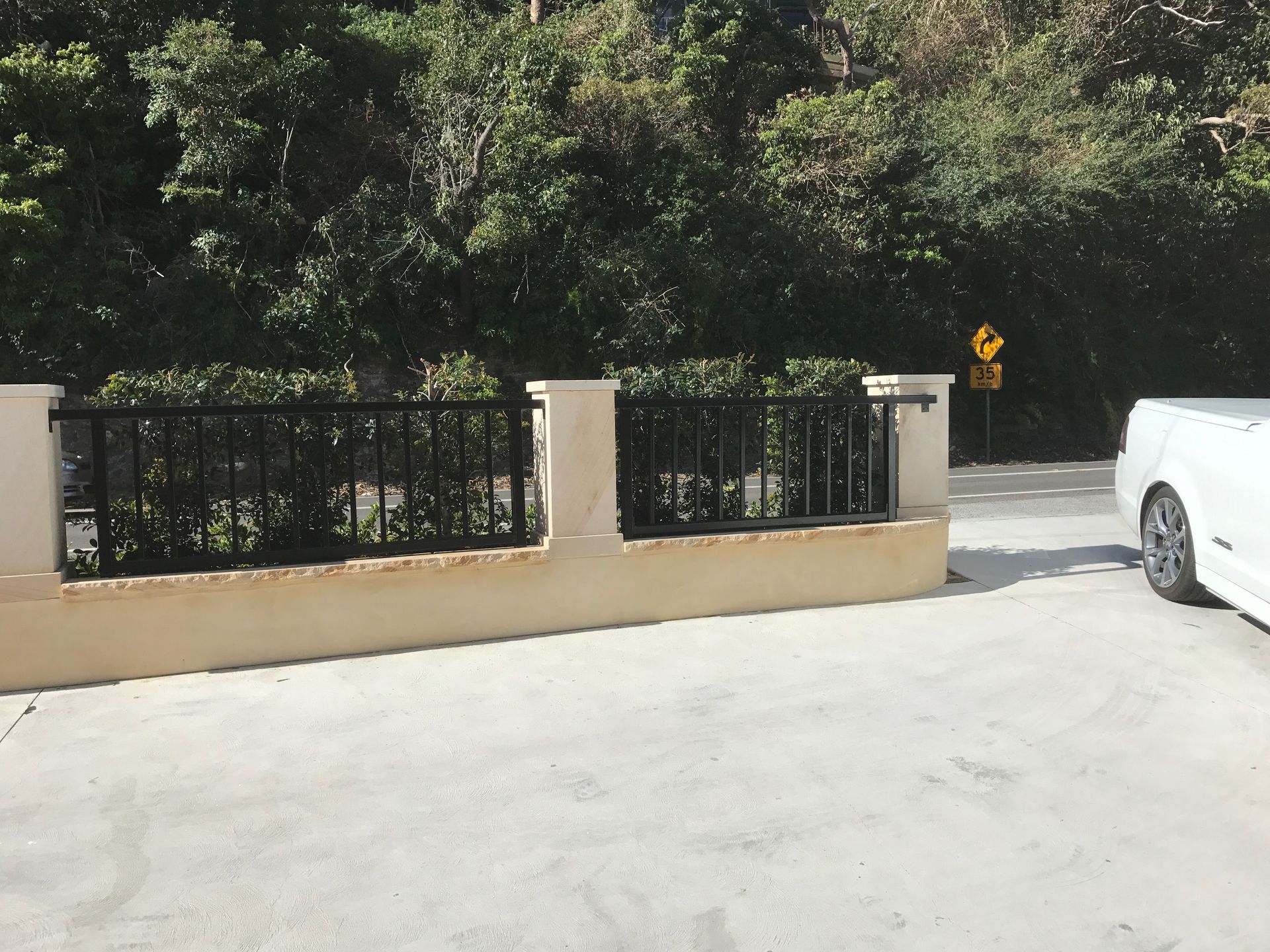 A white car is parked in a parking lot next to a fence