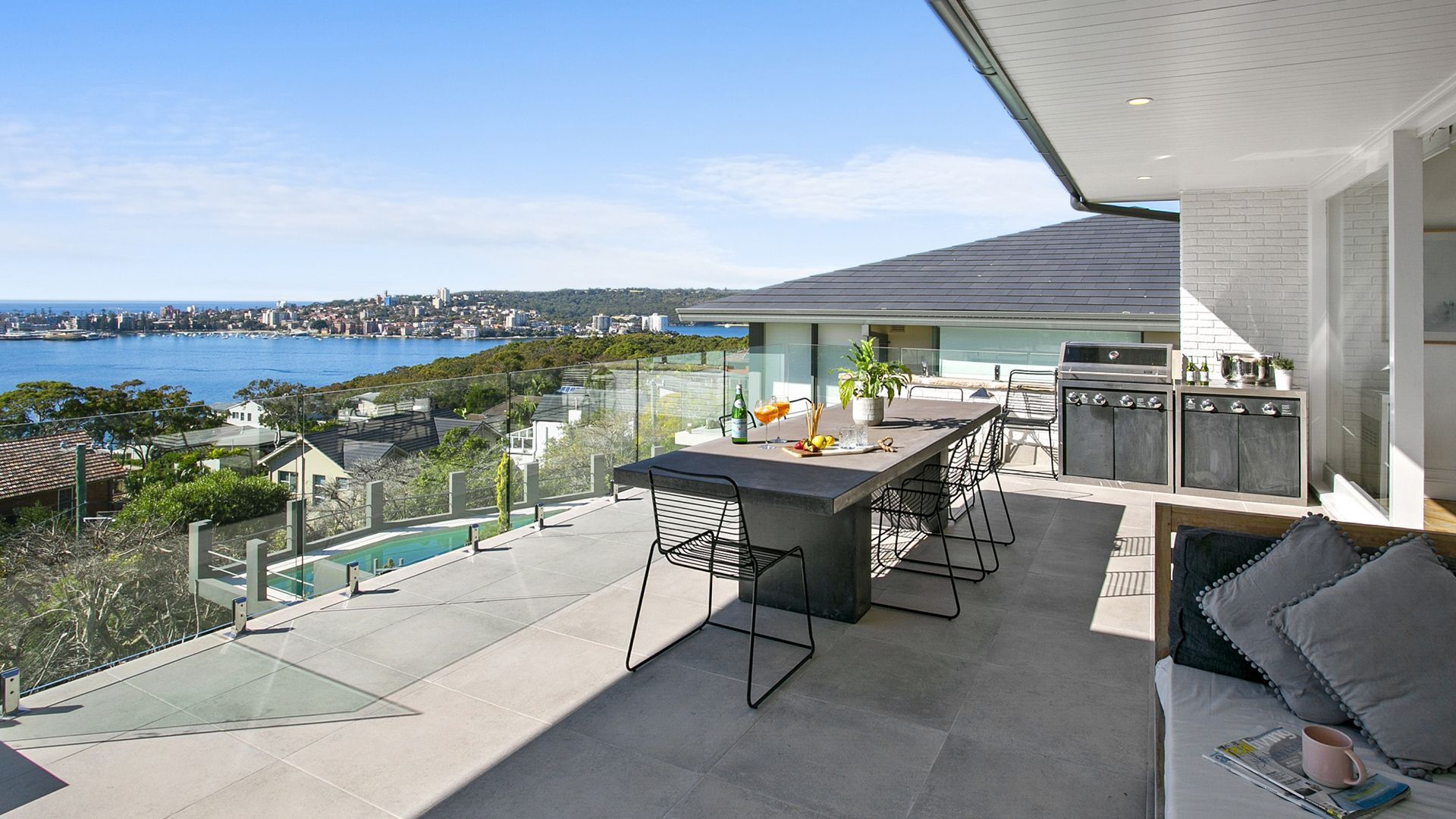 A patio with a table and chairs and a view of the ocean.