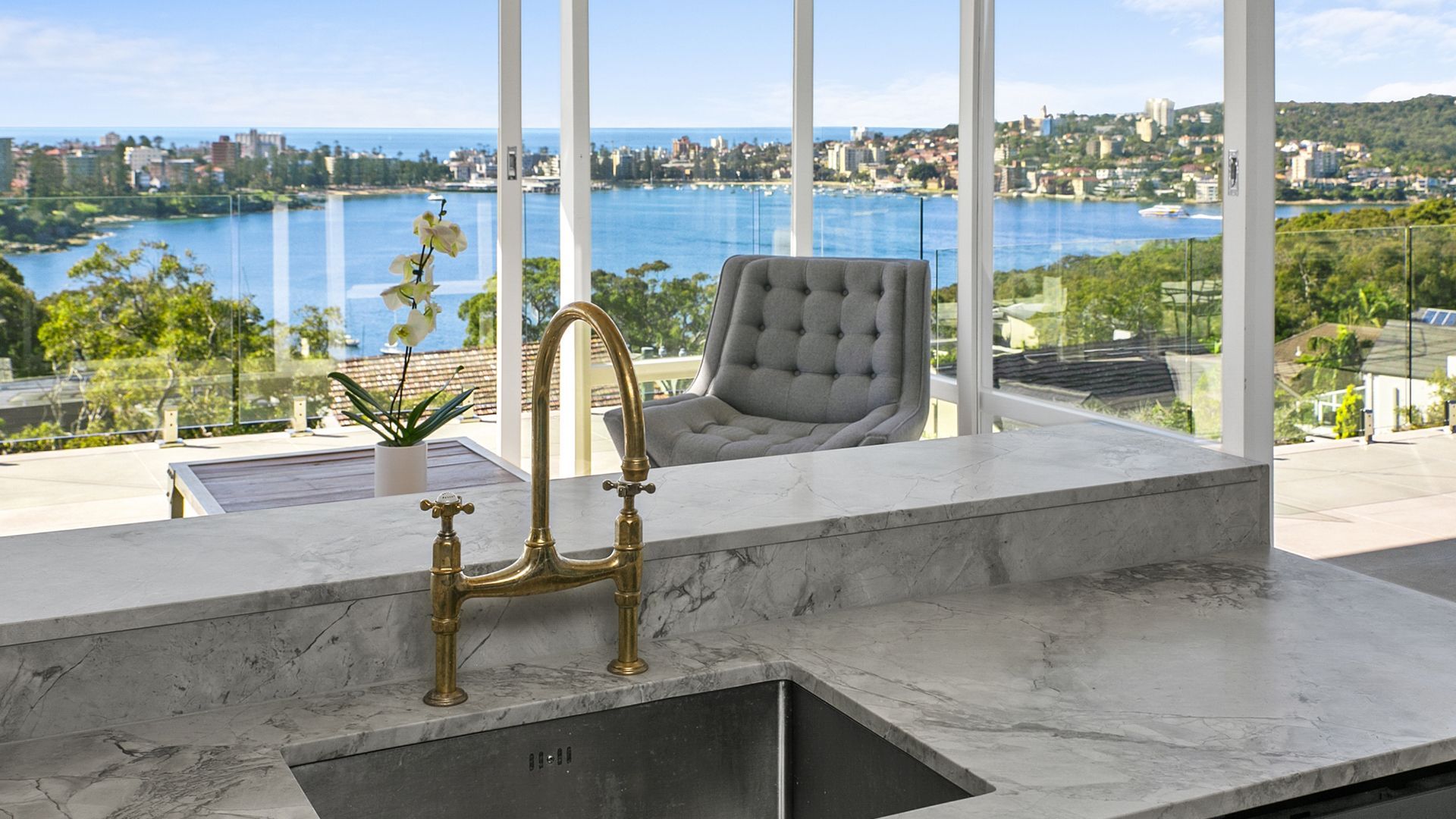 A kitchen with a sink and a view of the ocean.