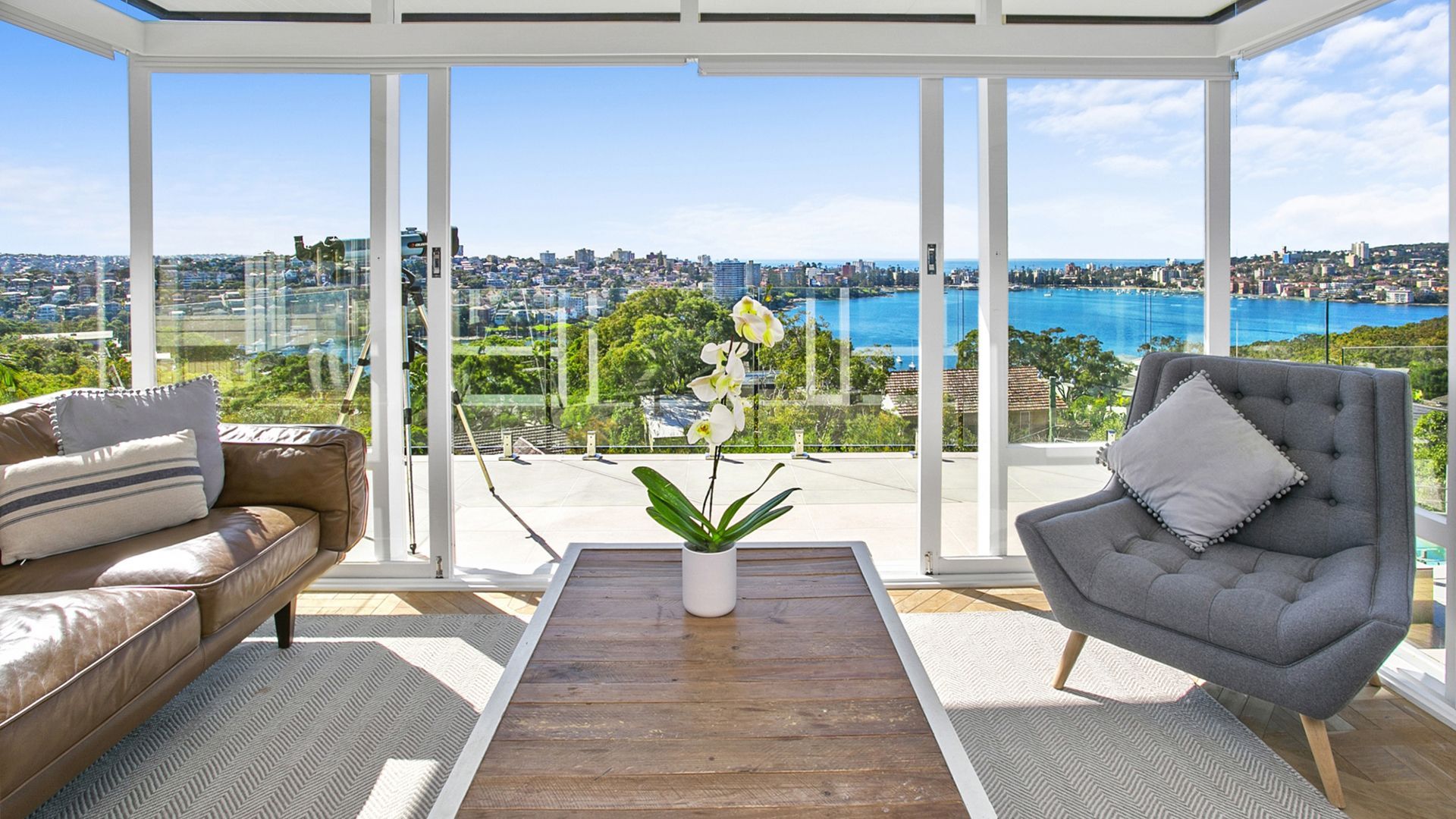 A living room with a couch , chair and table with a view of the ocean.