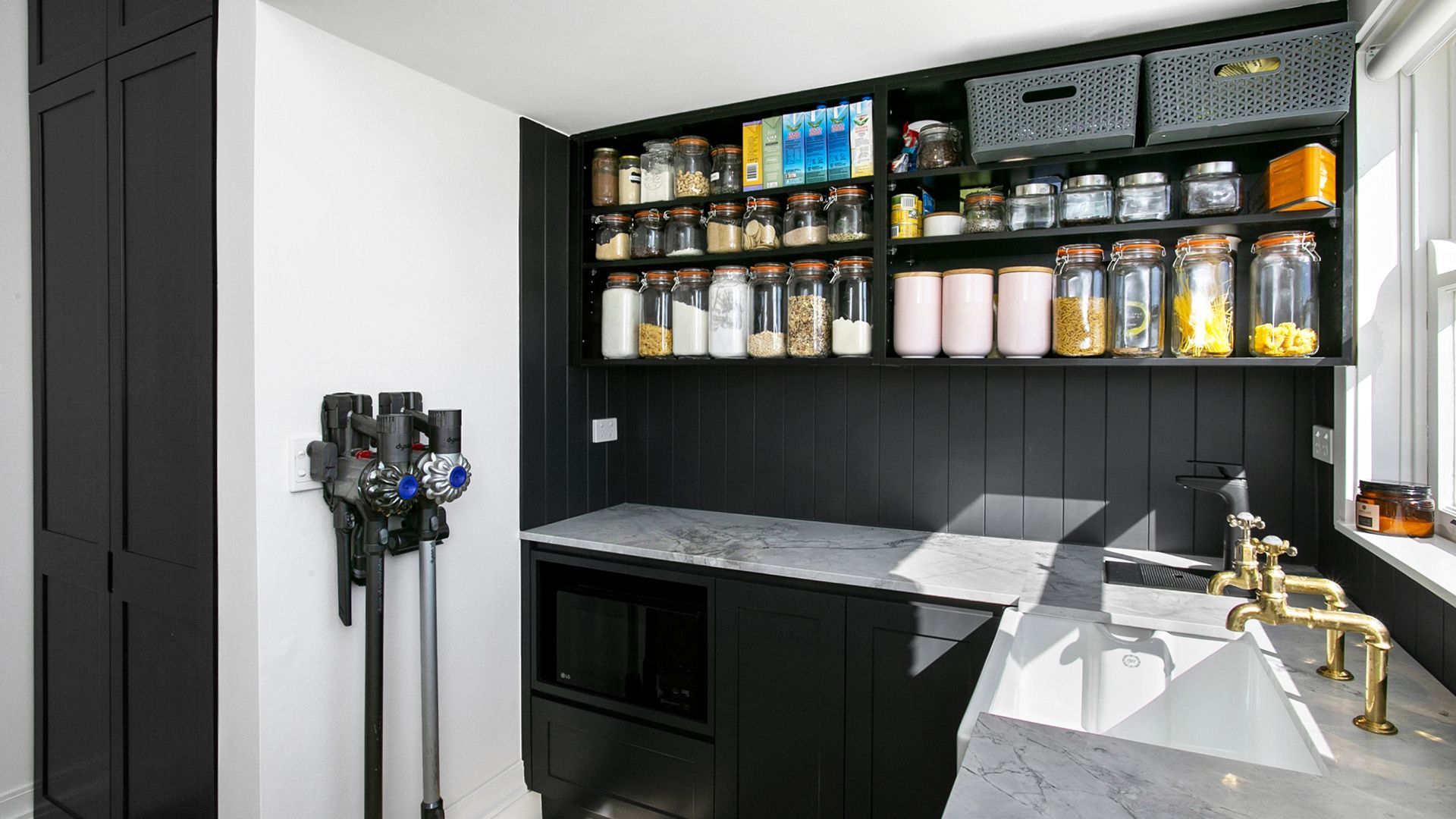 A kitchen with black cabinets , a sink , and a vacuum cleaner.