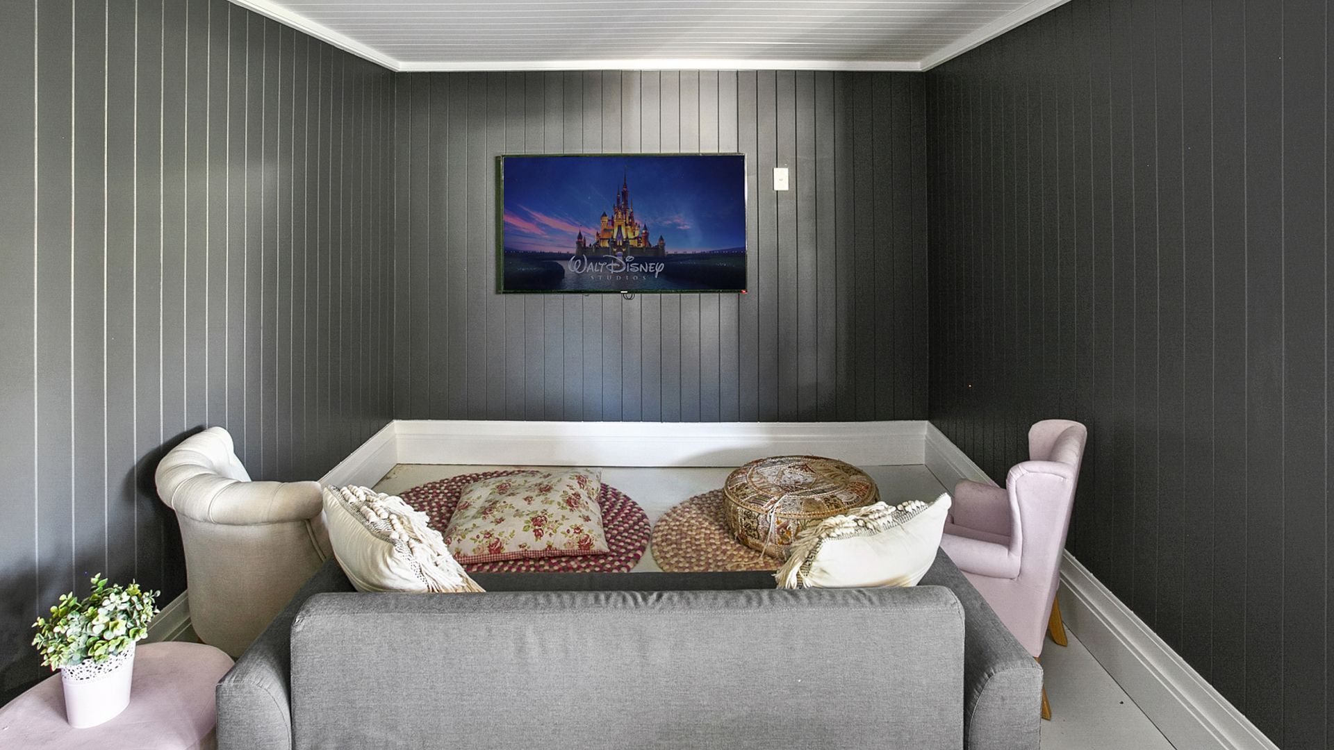 A living room with a couch , chairs and a television on the wall.