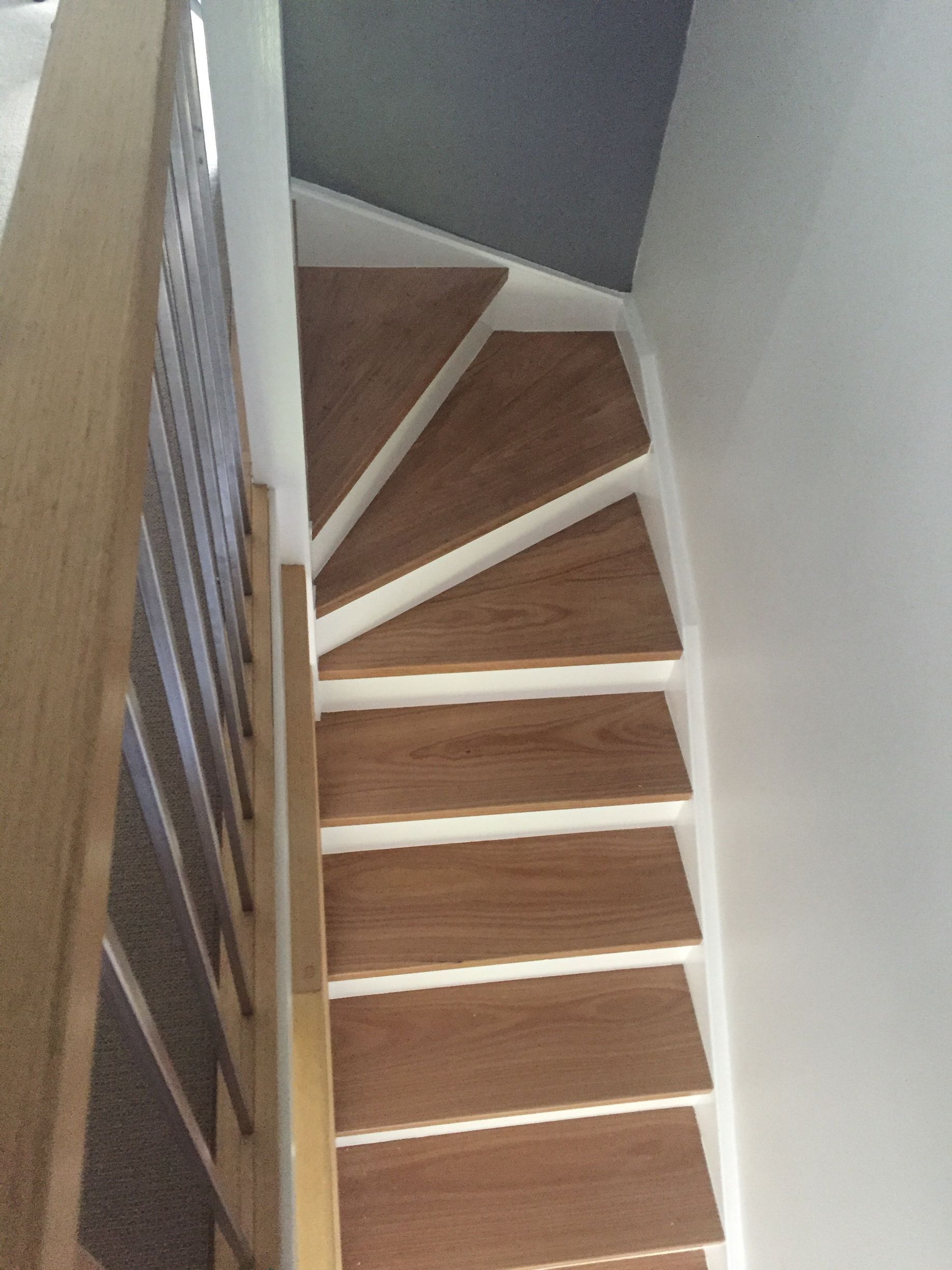 A spiral staircase with wooden steps and a white railing.