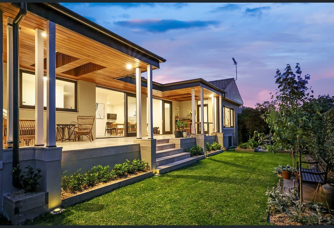 A house with a porch and a large lawn in front of it.