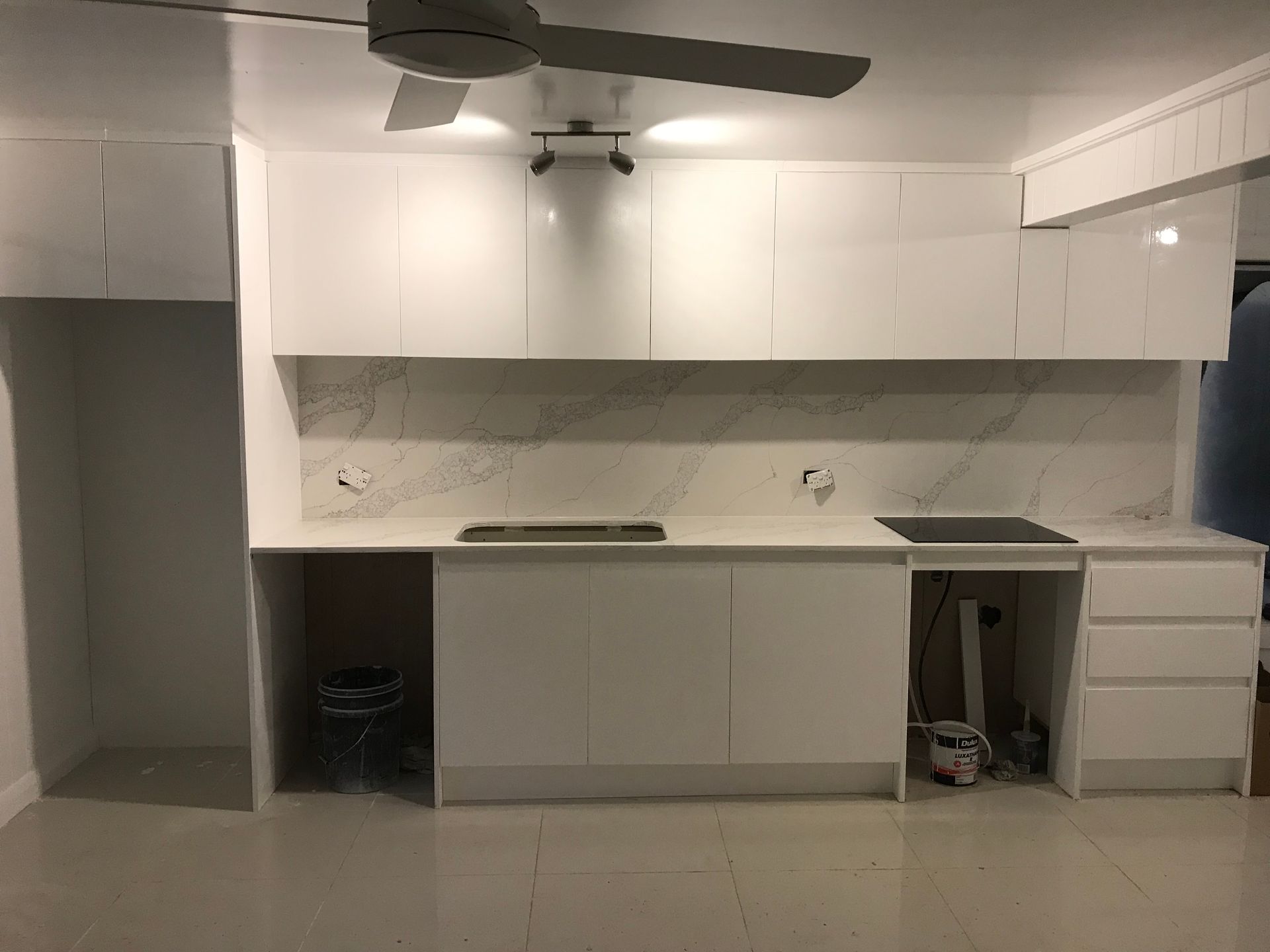 A kitchen with white cabinets and a ceiling fan.