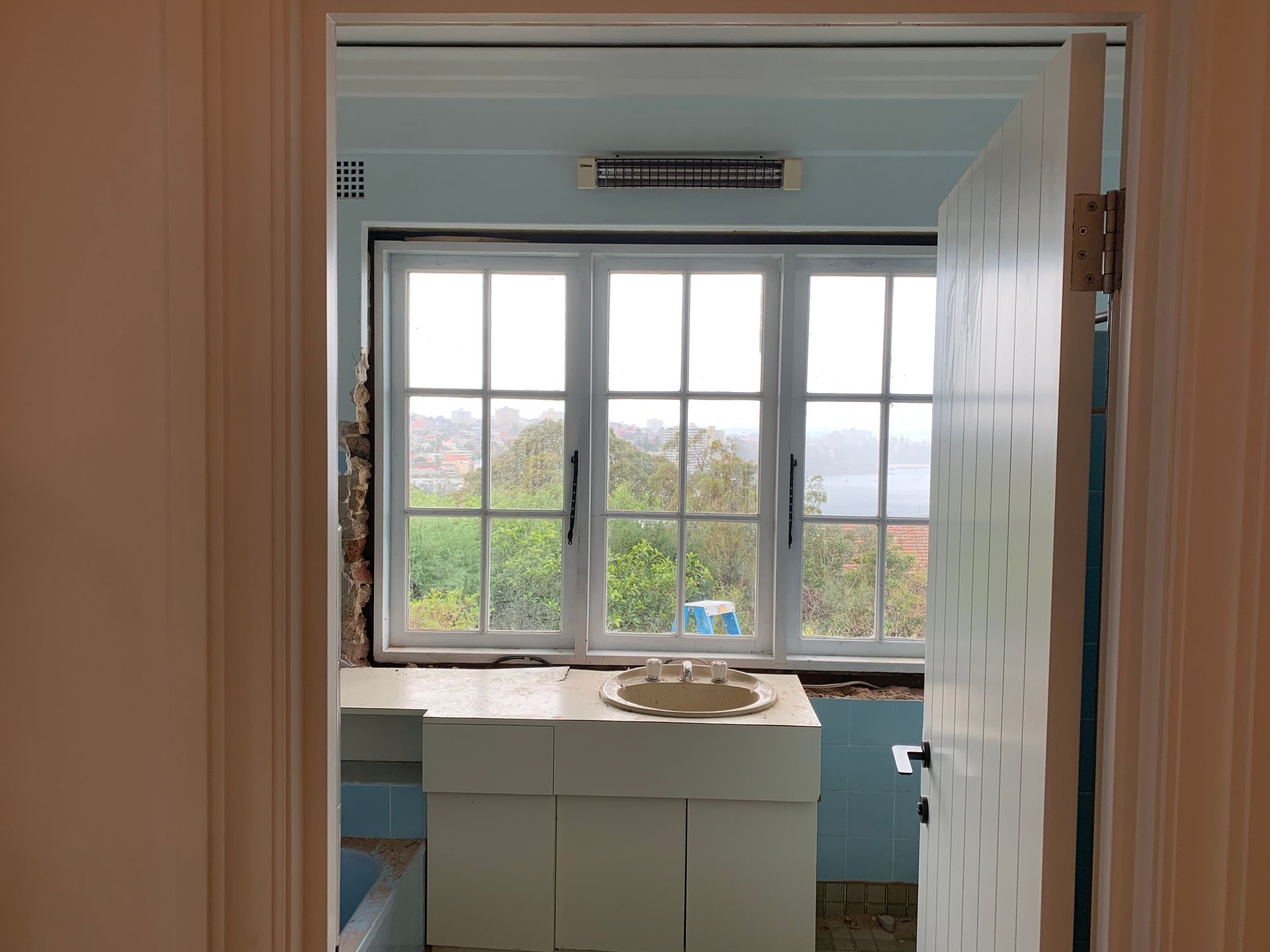A bathroom with a sink and a window with a view of the ocean.