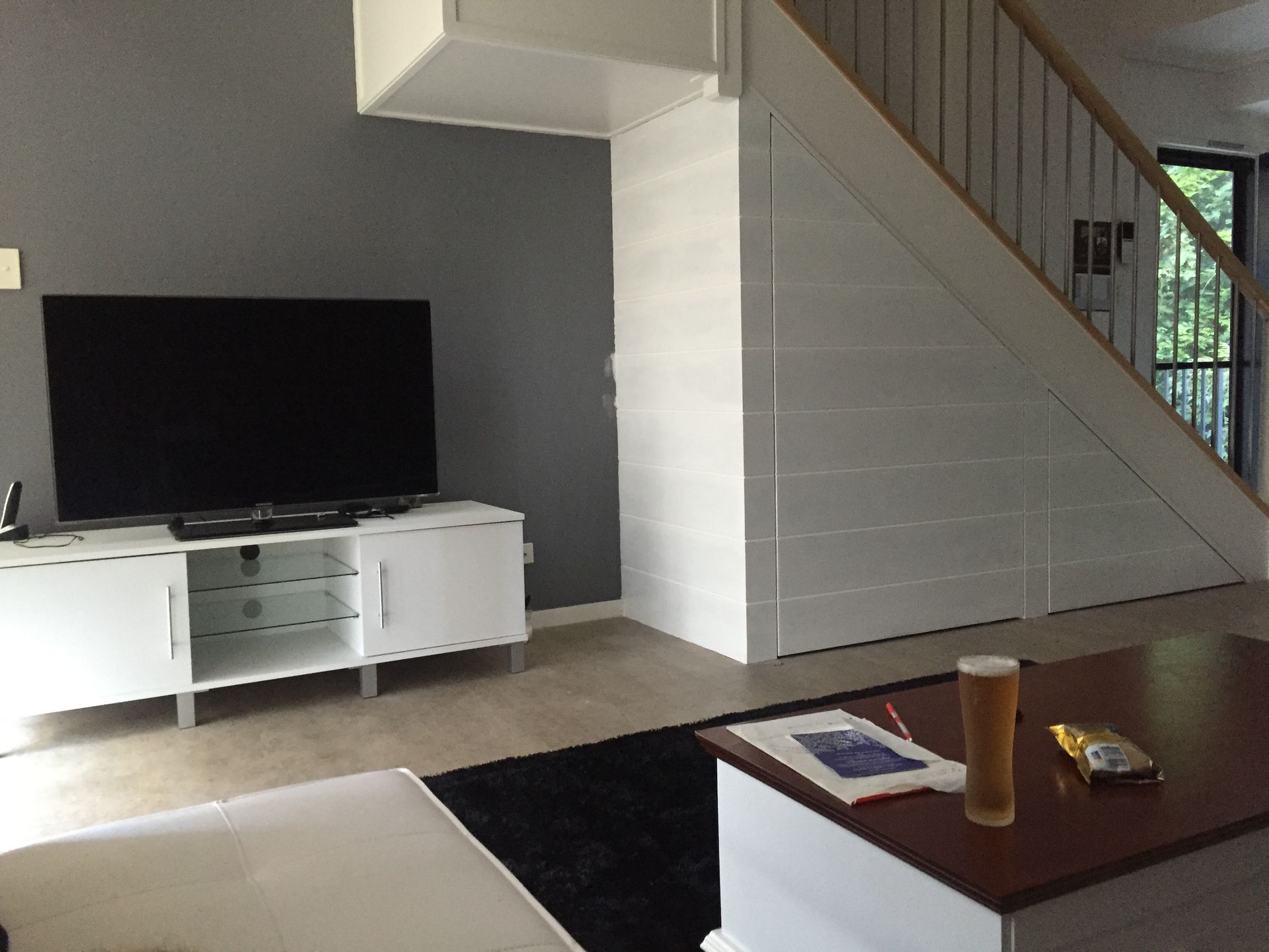 A living room with stairs and a flat screen tv