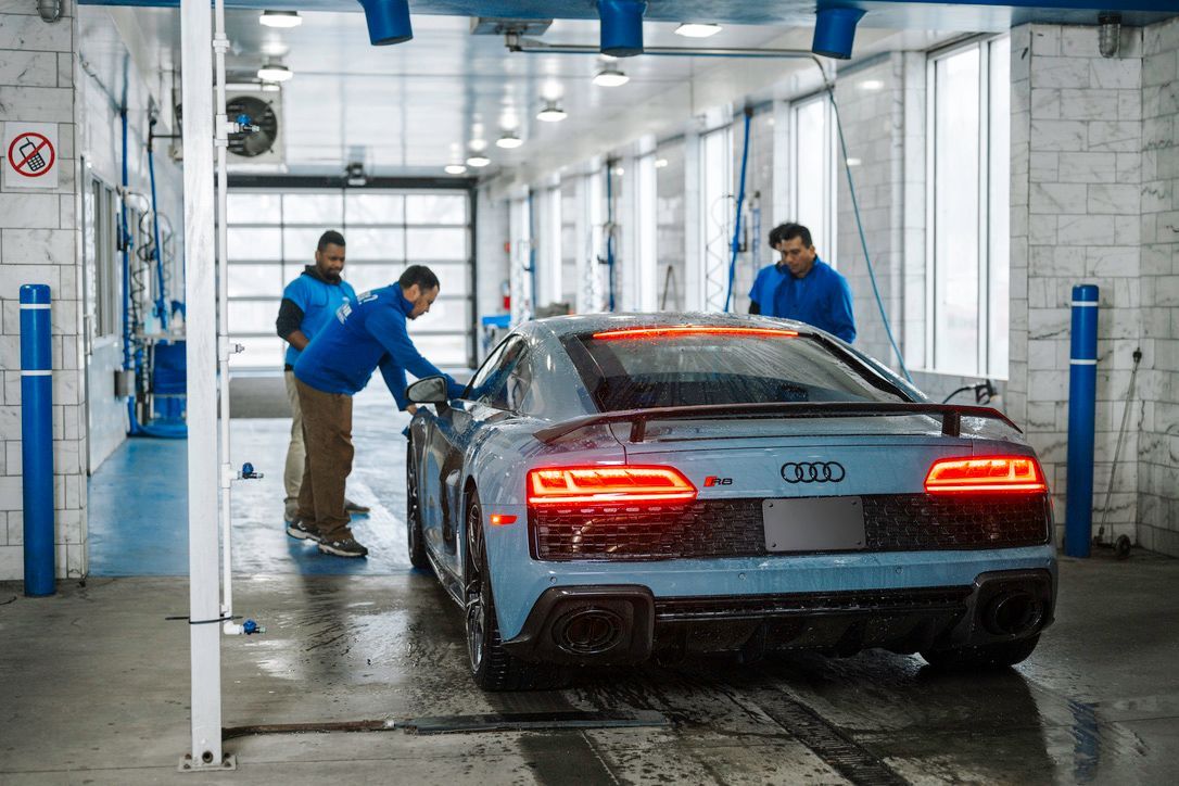 A man is washing a car in a car wash.