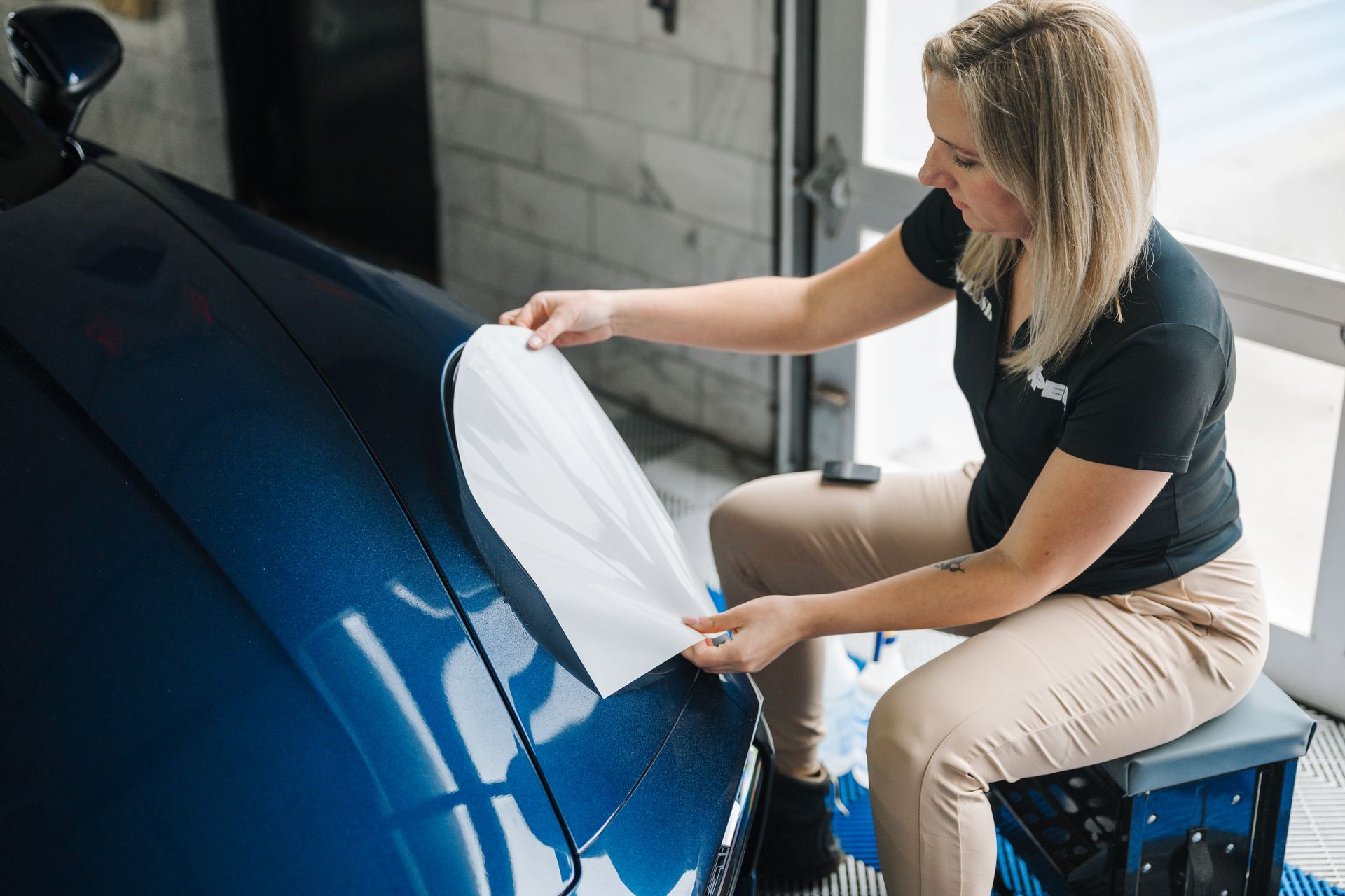 A man is applying a protective film to the headlights of a mercedes benz.