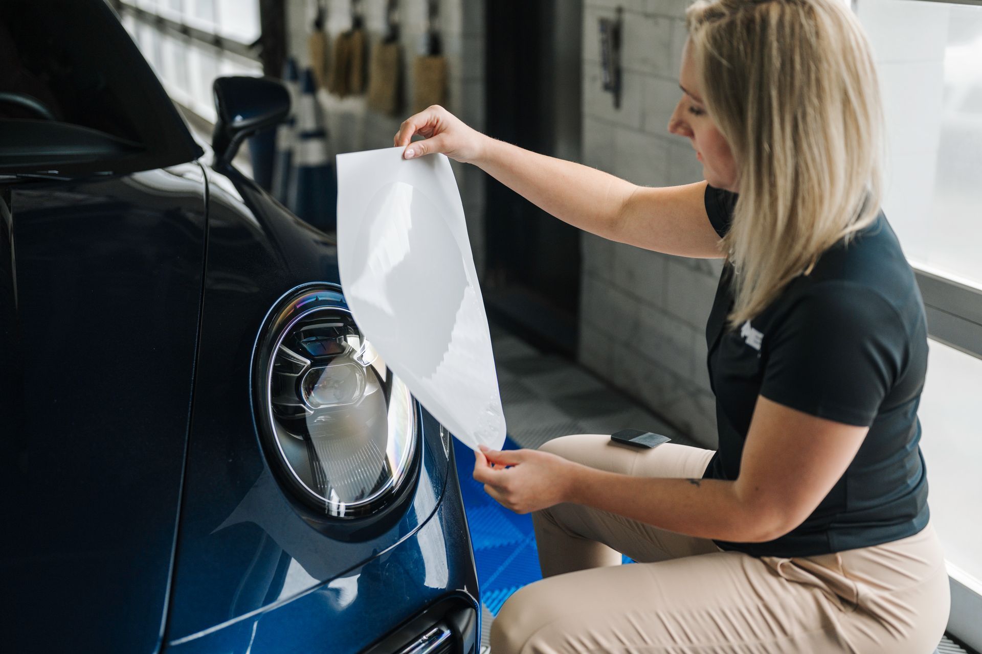 A woman is wrapping a car with a piece of paper.