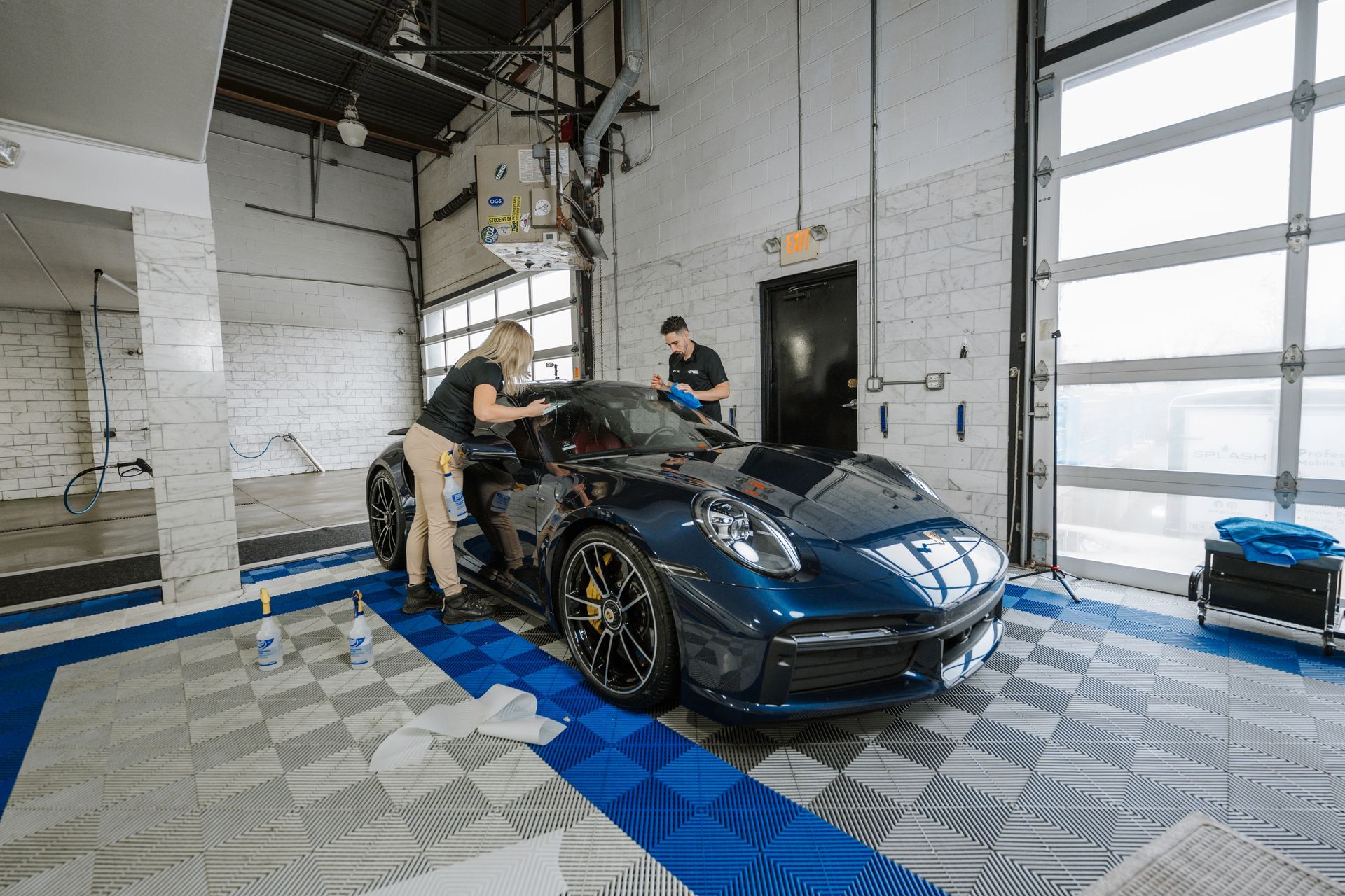 A man and a woman are working on a car in a garage.