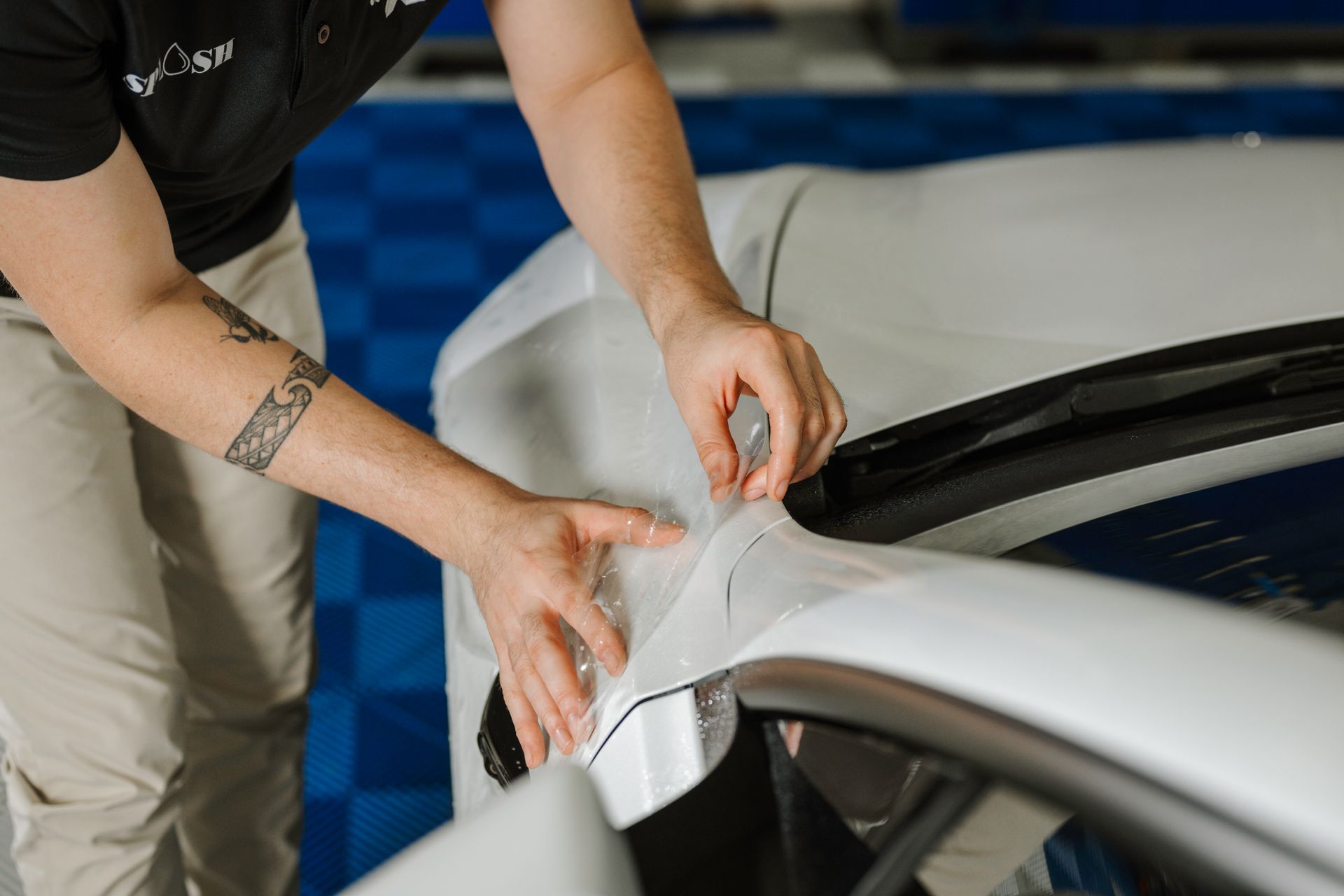 A man is wrapping a car with plastic wrap.