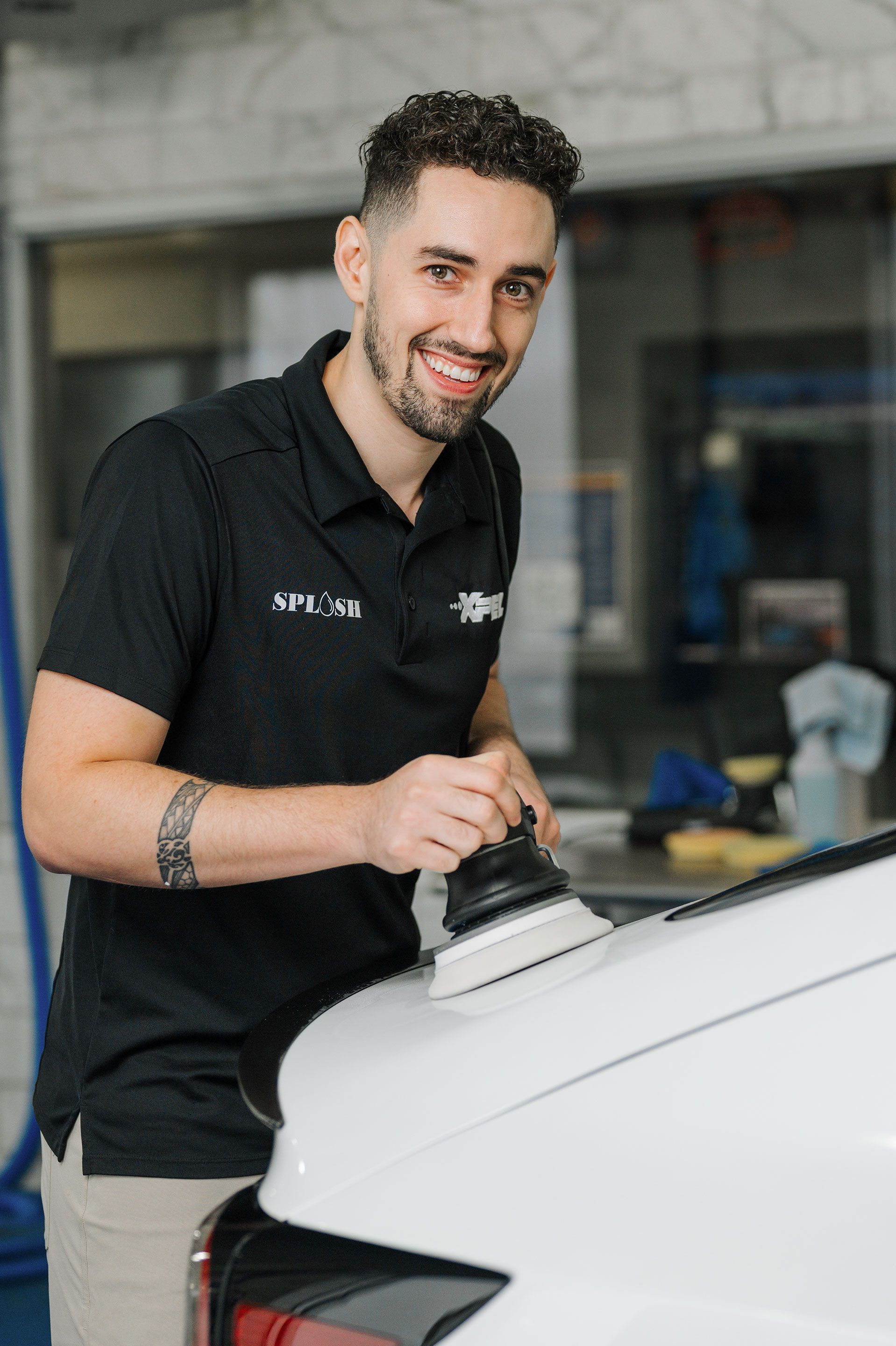 A man is polishing the hood of a white car.