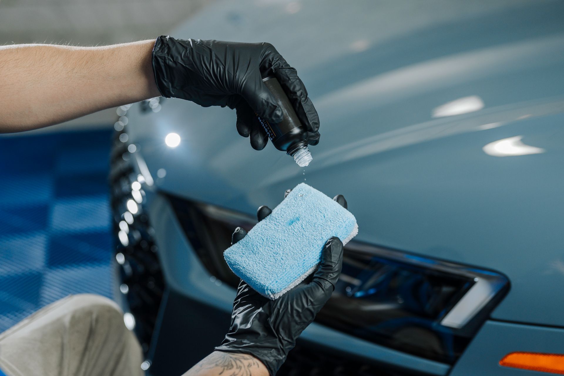 A person is cleaning a car with a sponge and a spray bottle.