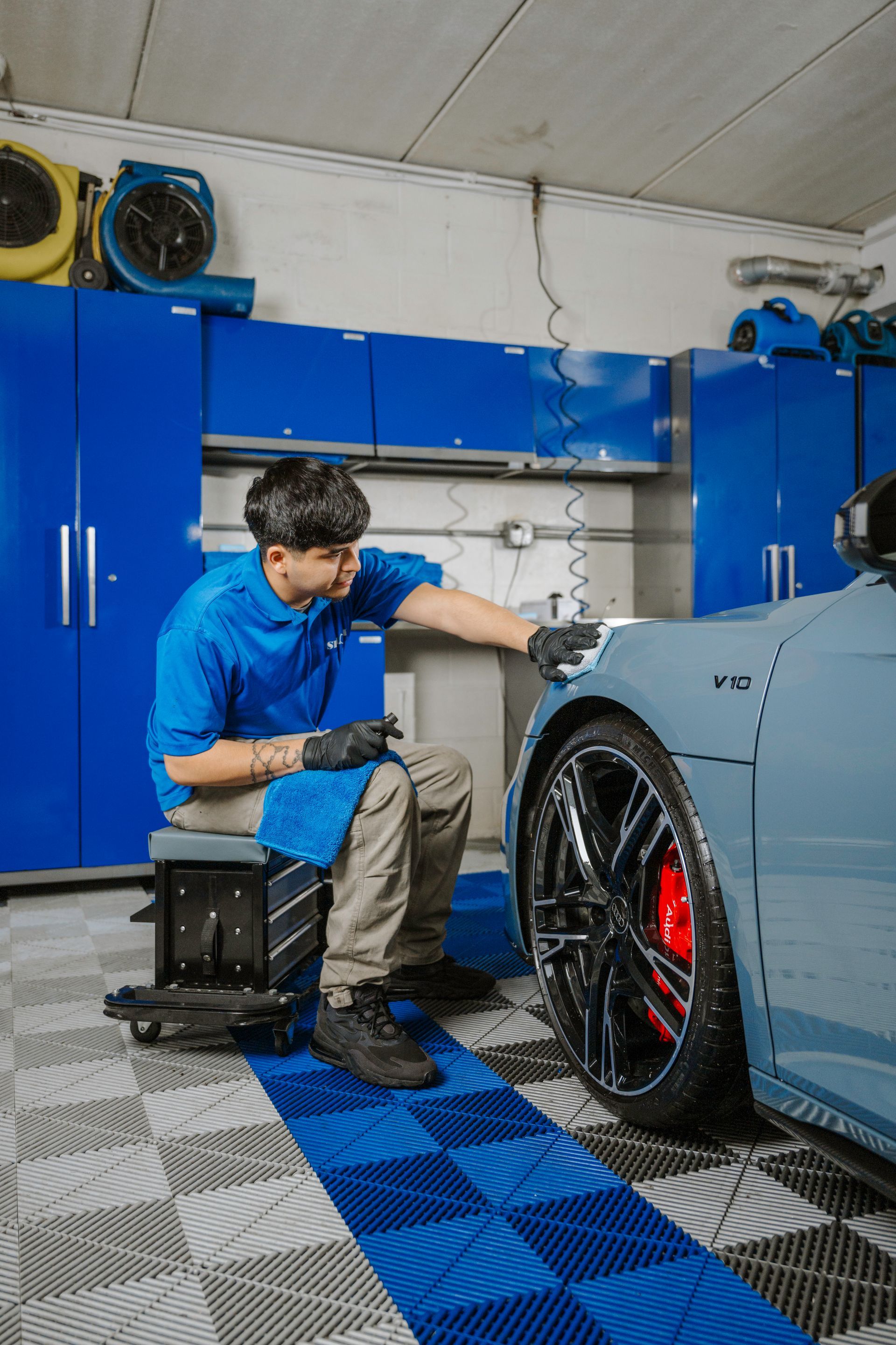 A man is cleaning a car in a garage.