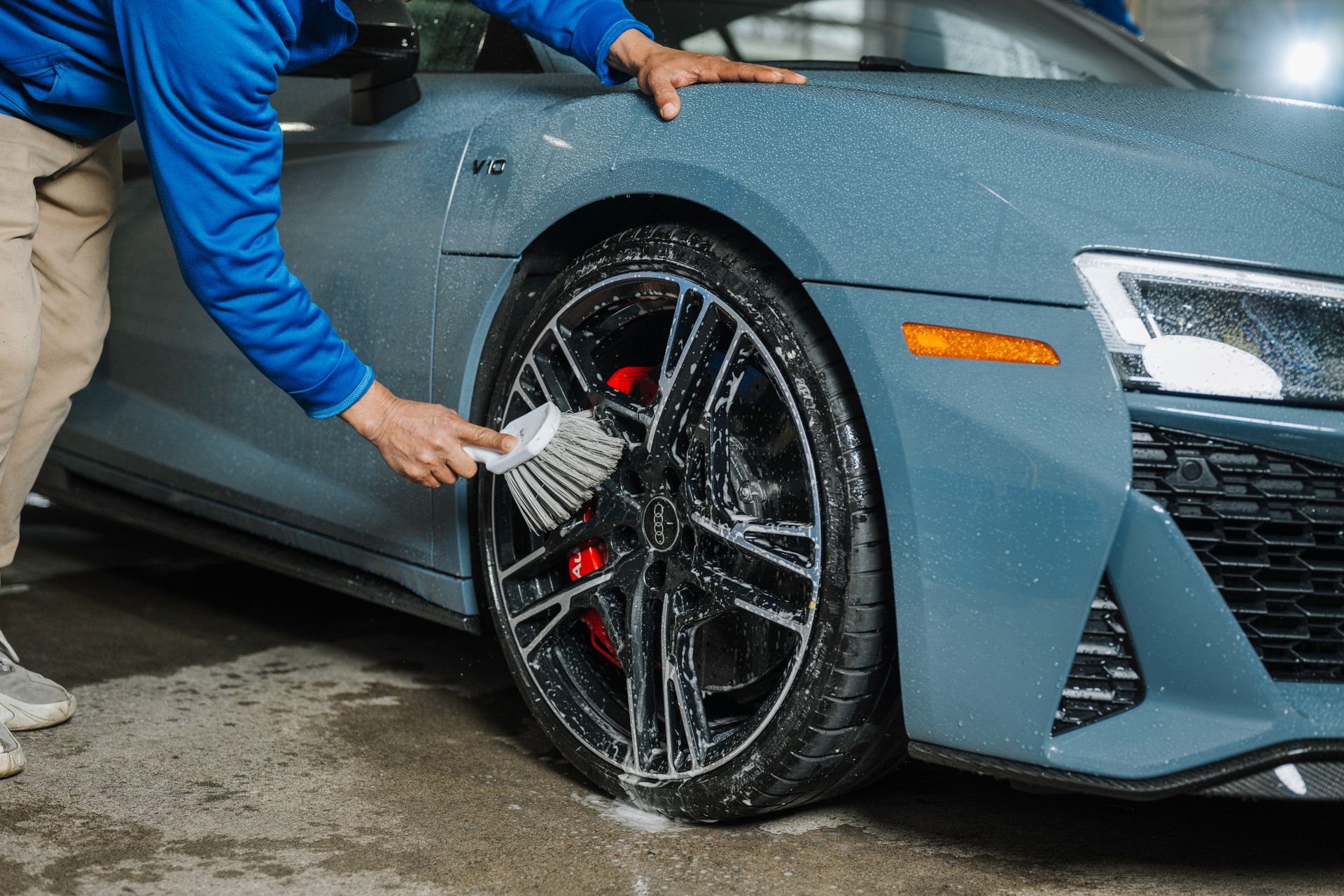 A man is cleaning the wheel of a car with a brush.