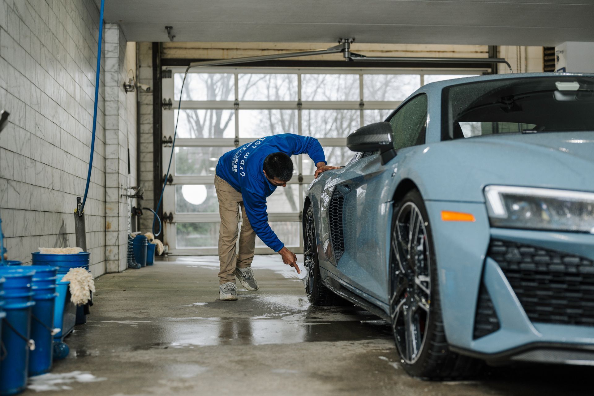 A man is washing a car in a garage.