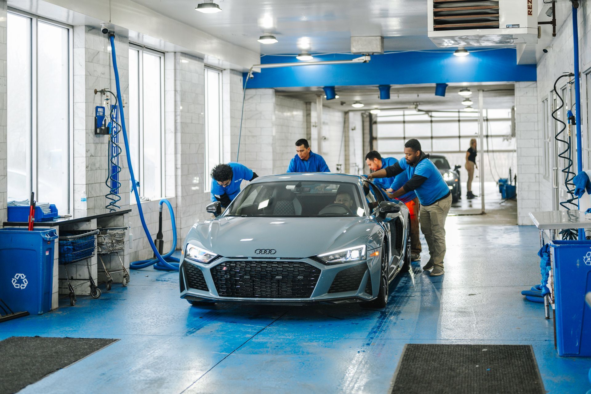 A group of men are washing a car in a car wash.