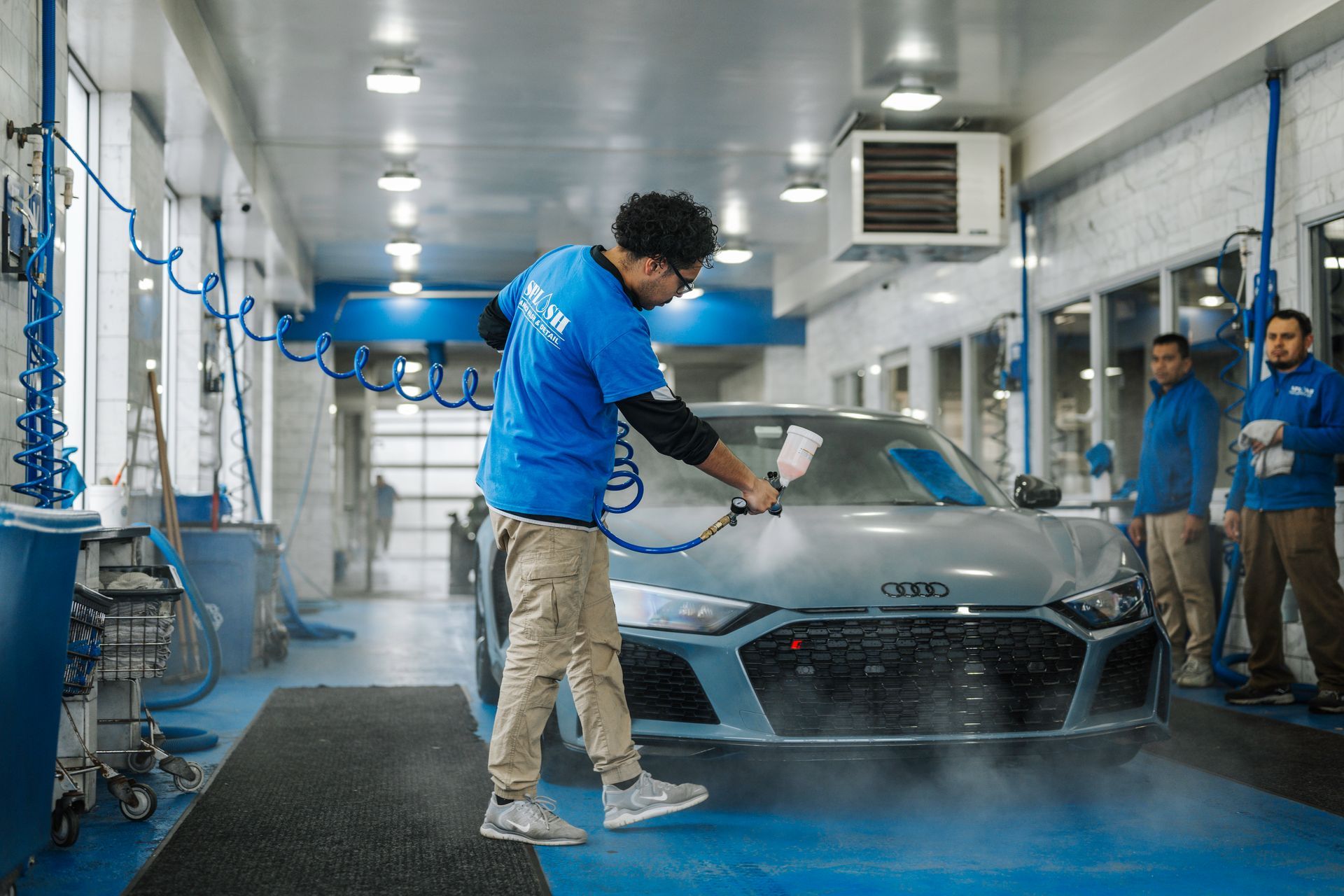 A man is washing a car in a car wash.