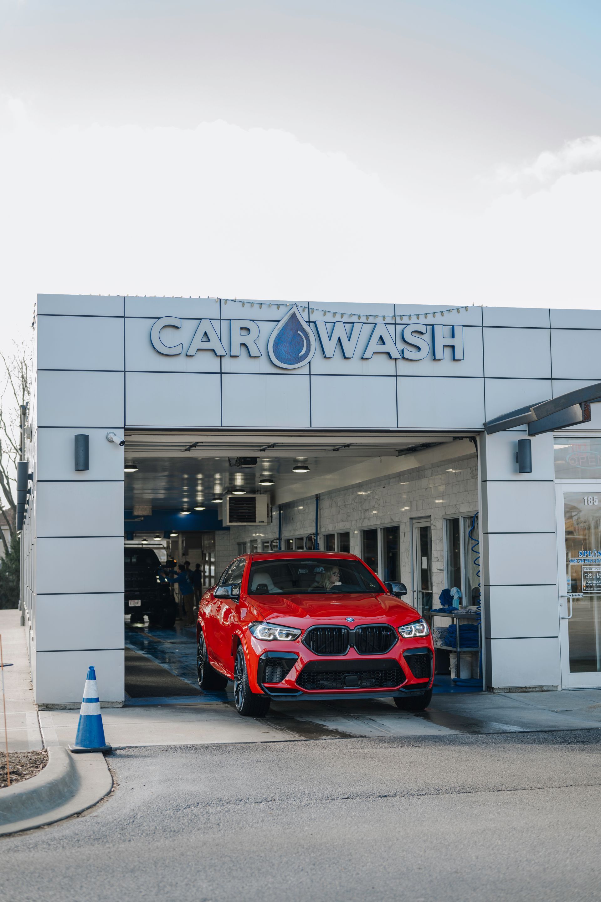 A red car is parked in front of a car wash.