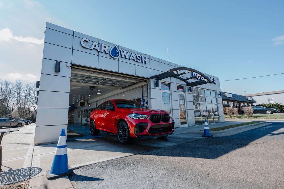 A red car is parked in front of a car wash.