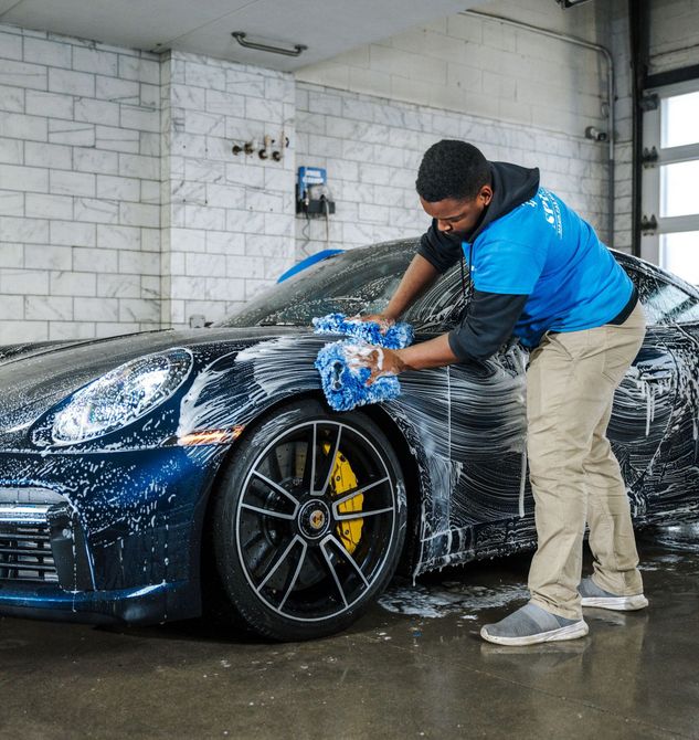 A man in a blue shirt is washing a car