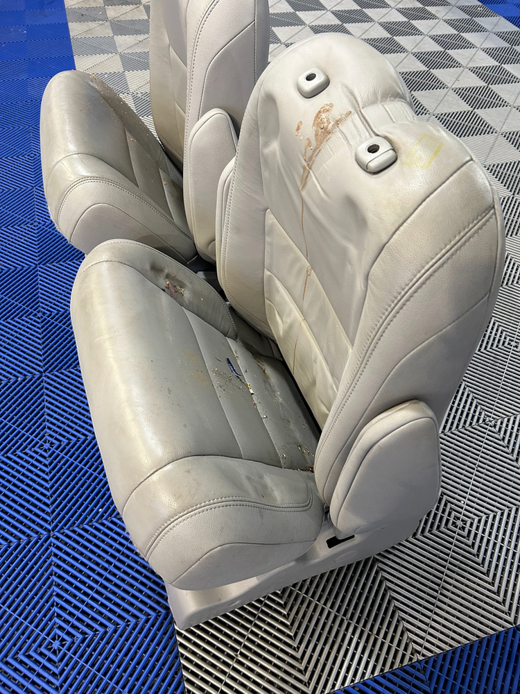 A pair of white leather seats are sitting on a blue tiled floor.