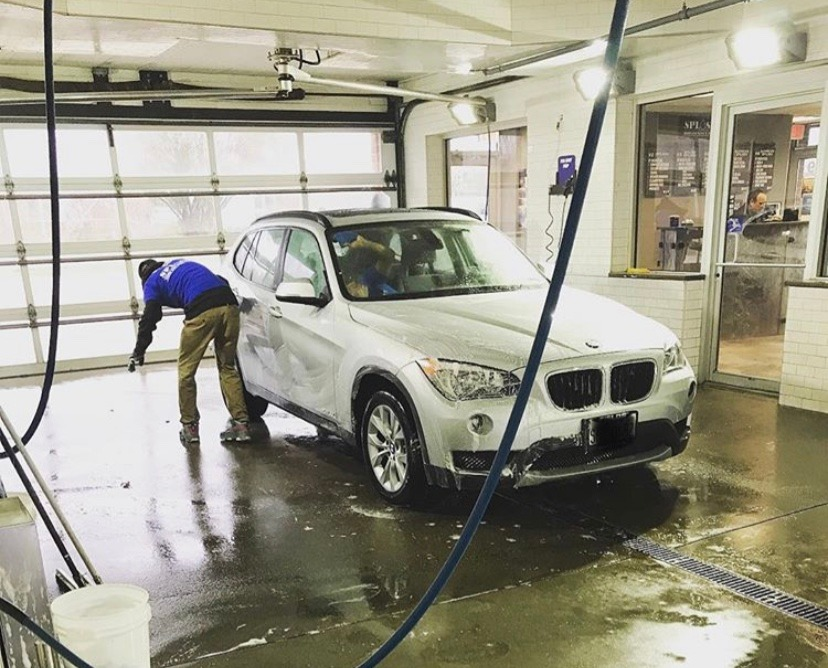 A man is washing a bmw in a car wash