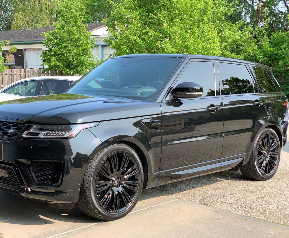 A black range rover sport is parked in a driveway.