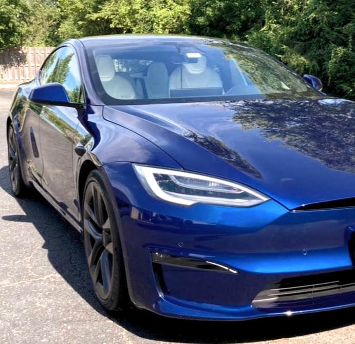 A blue tesla model s is parked on the side of the road