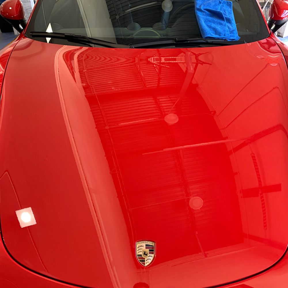 A close up of the hood of a red sports car in a garage.