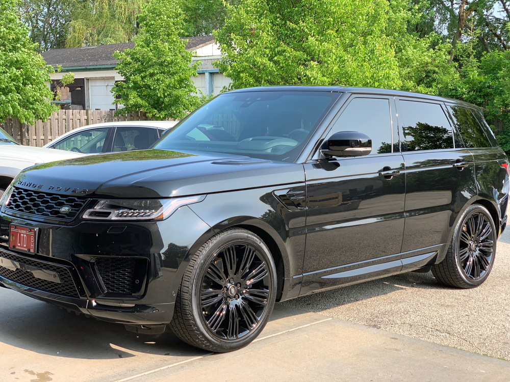 A black range rover sport is parked in a driveway.