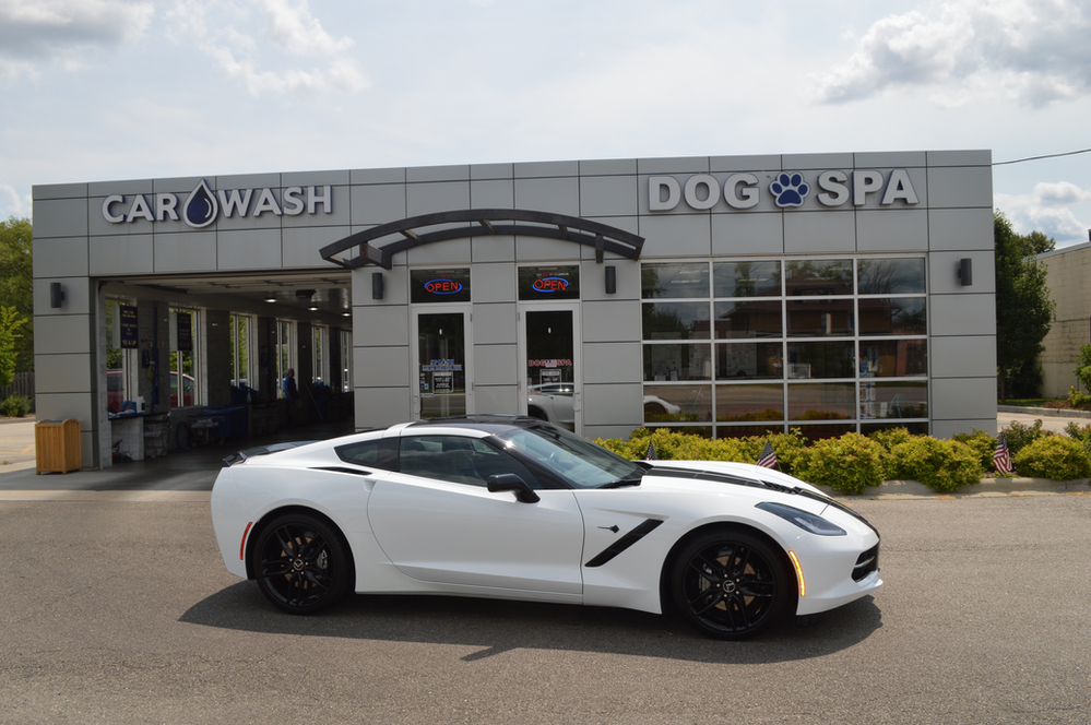 A white corvette is parked in front of a car wash.