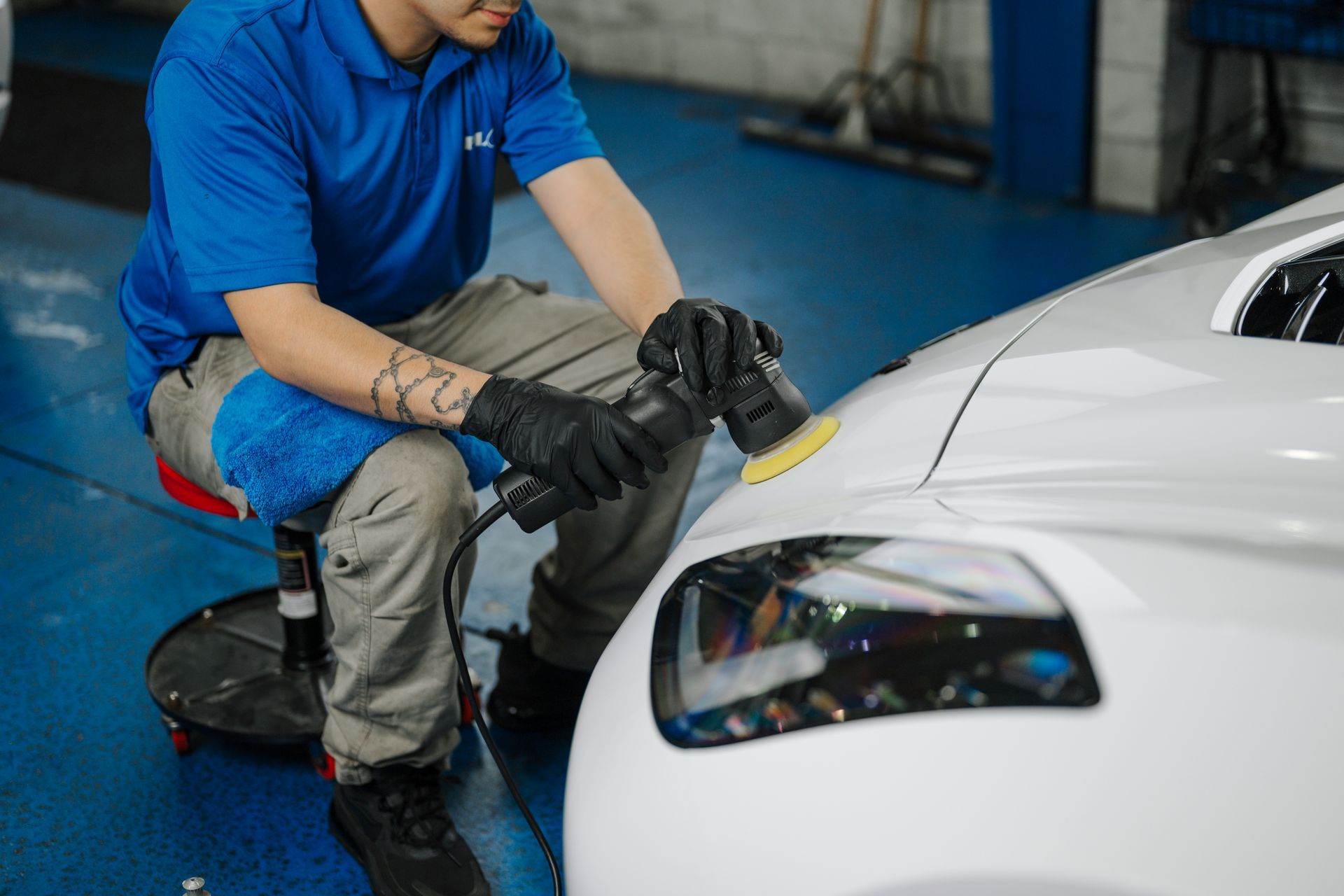 A man is polishing the front of a white car.