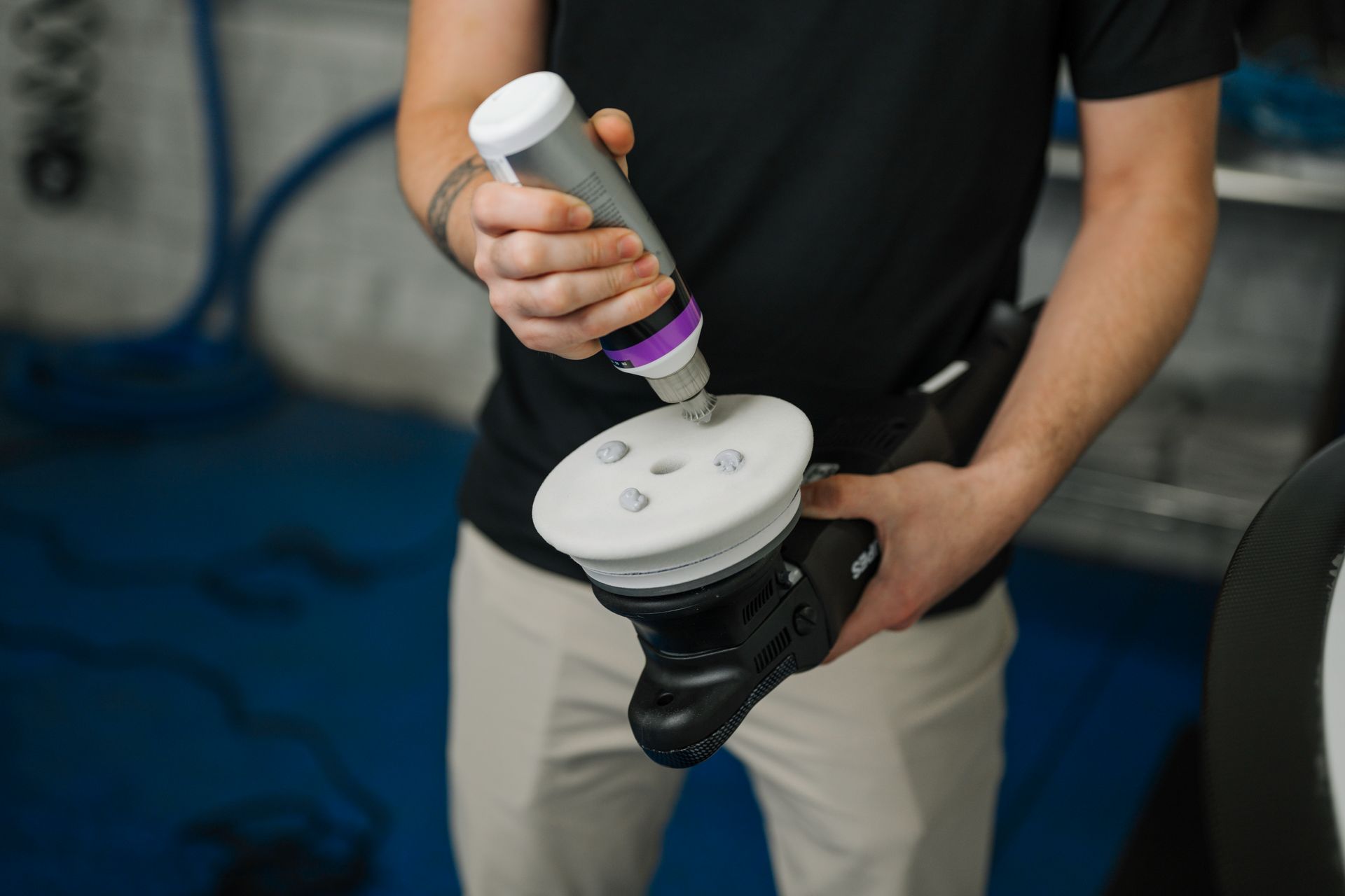 A man is holding a polisher and a bottle of polish.