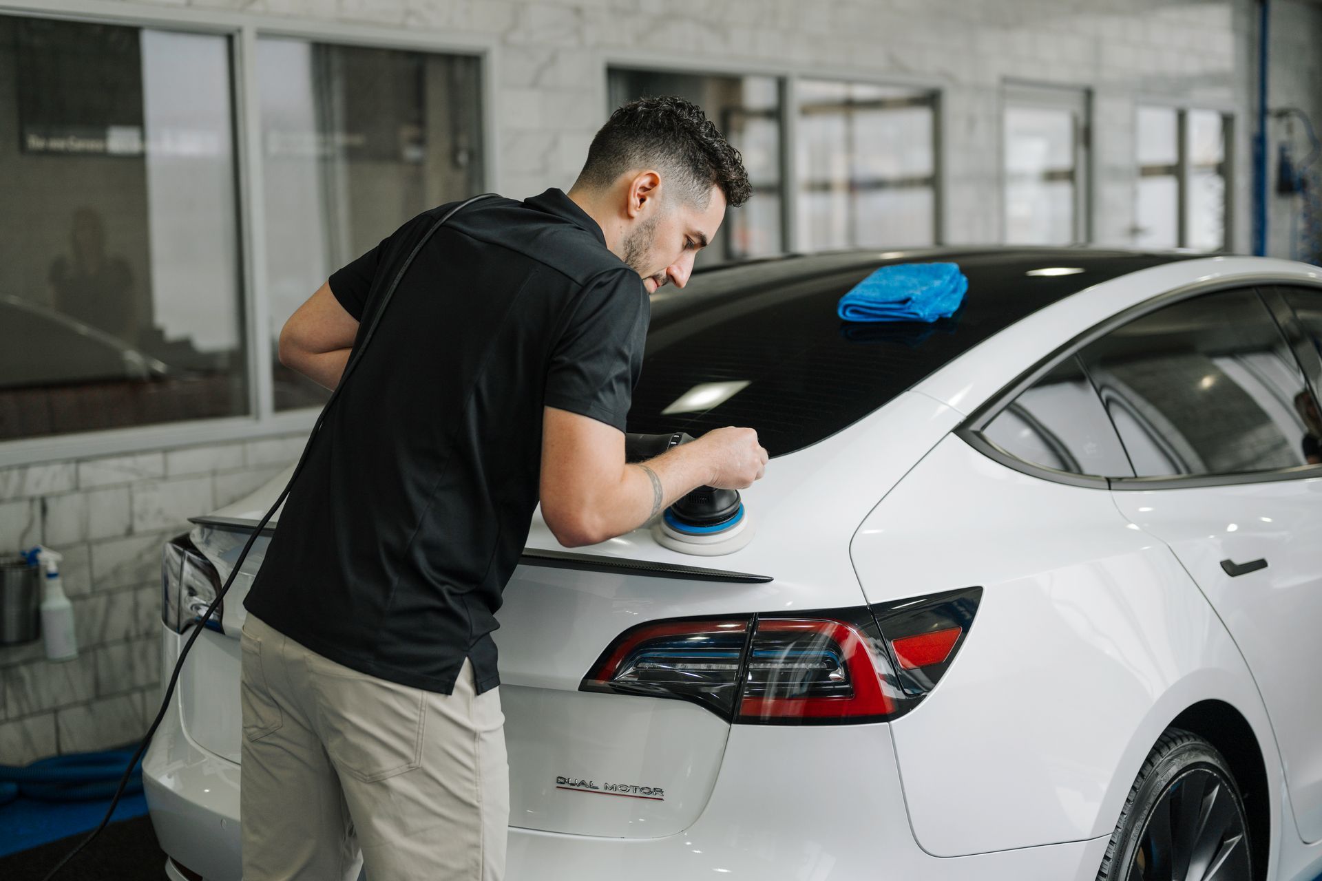 A man is polishing a white car in a garage.