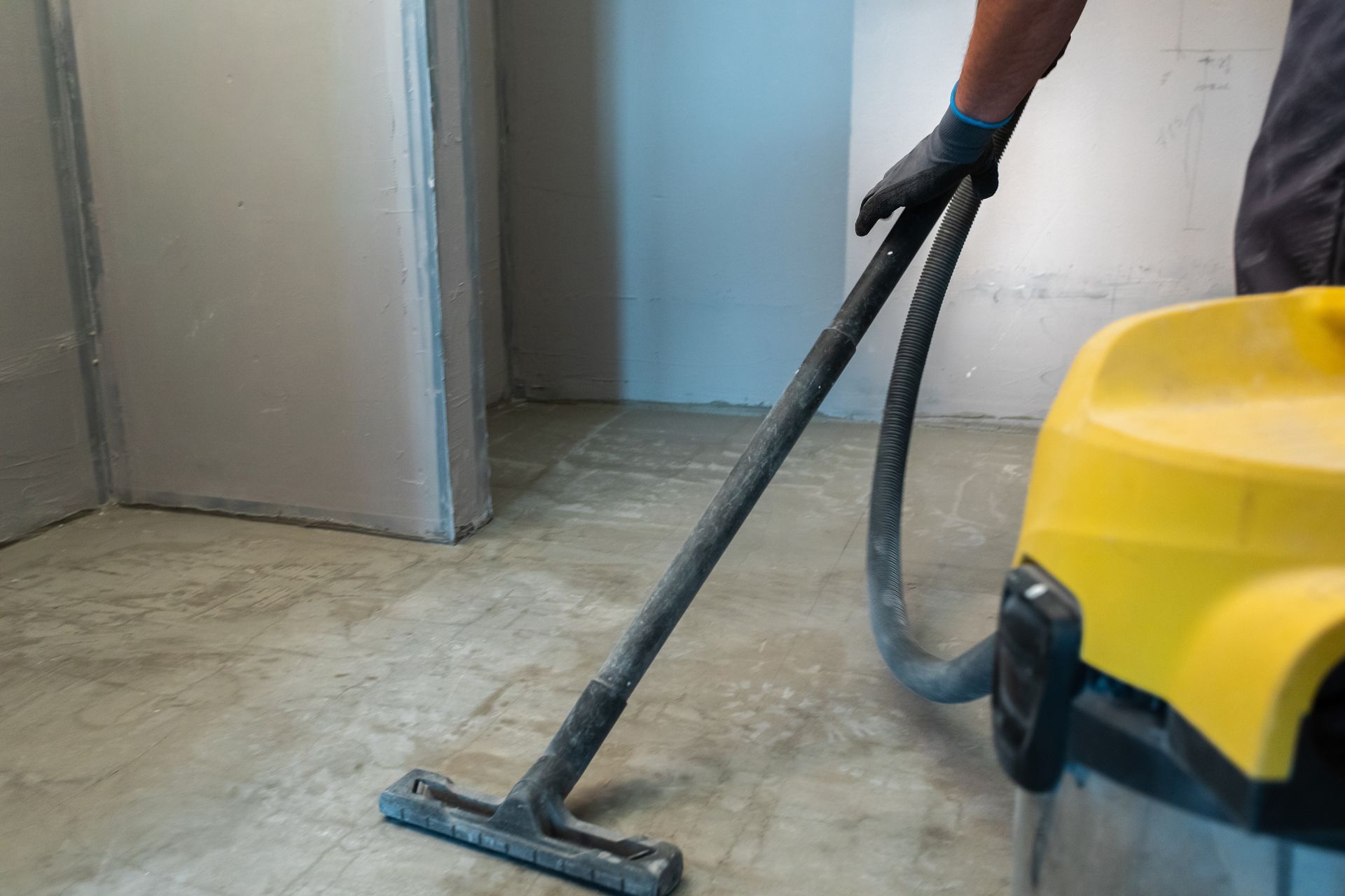 Someone using a wet/dry vacuum on the floor after a construction project.