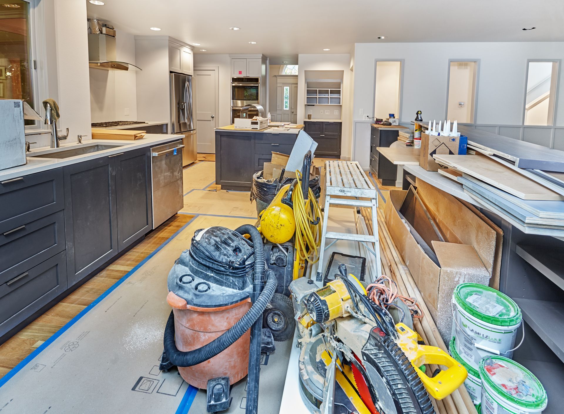 Construction gear neatly put aside in a freshly remodeled kitchen space. The kitchen is in need of a post construction cleaning.