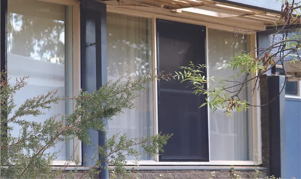 A house with a sliding screen door and a large window.