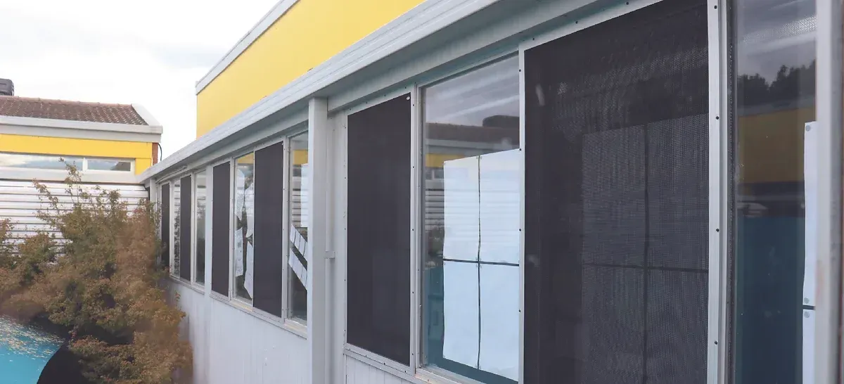 A building with a lot of windows and a pool in the background.