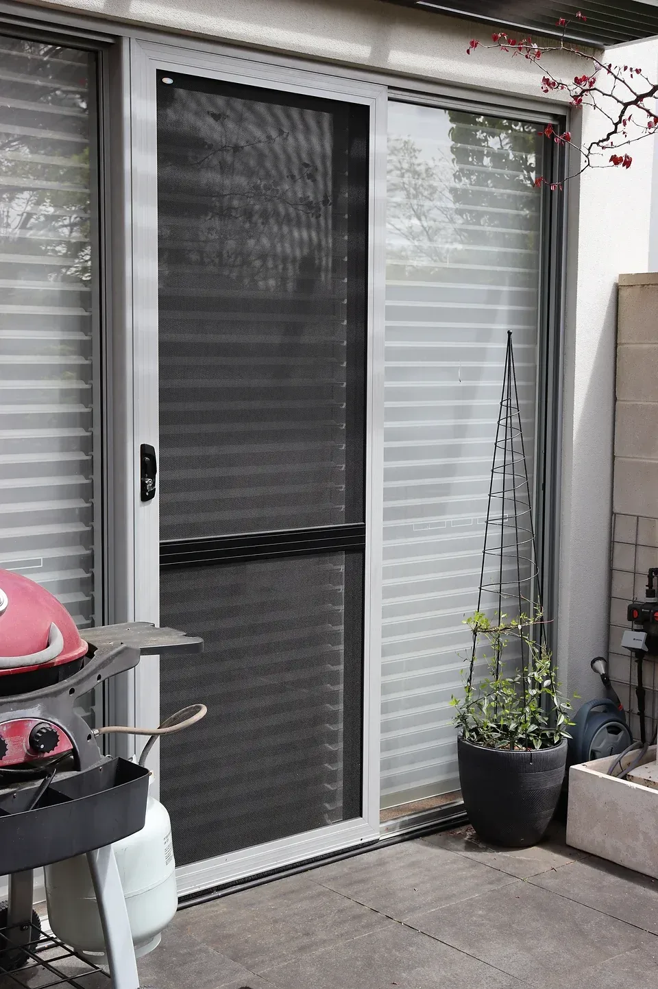 A patio with a sliding glass door and a grill.