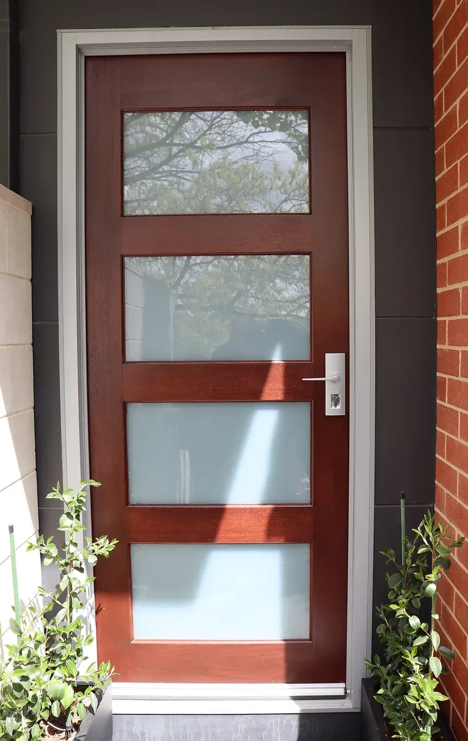 A wooden door with three windows and a brick wall behind it
