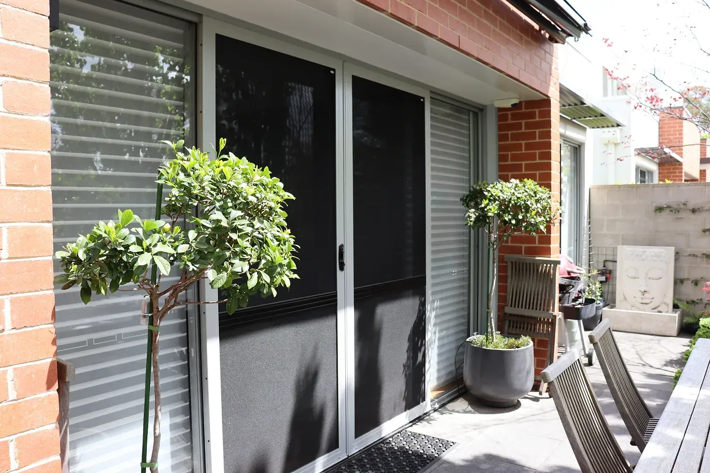 A patio with a table and chairs and a screen door.