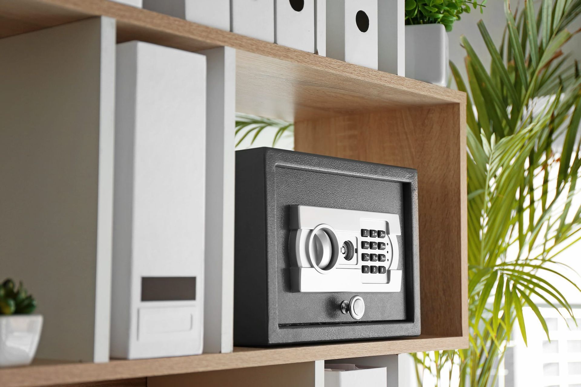 A digital safe is sitting on top of a wooden shelf.