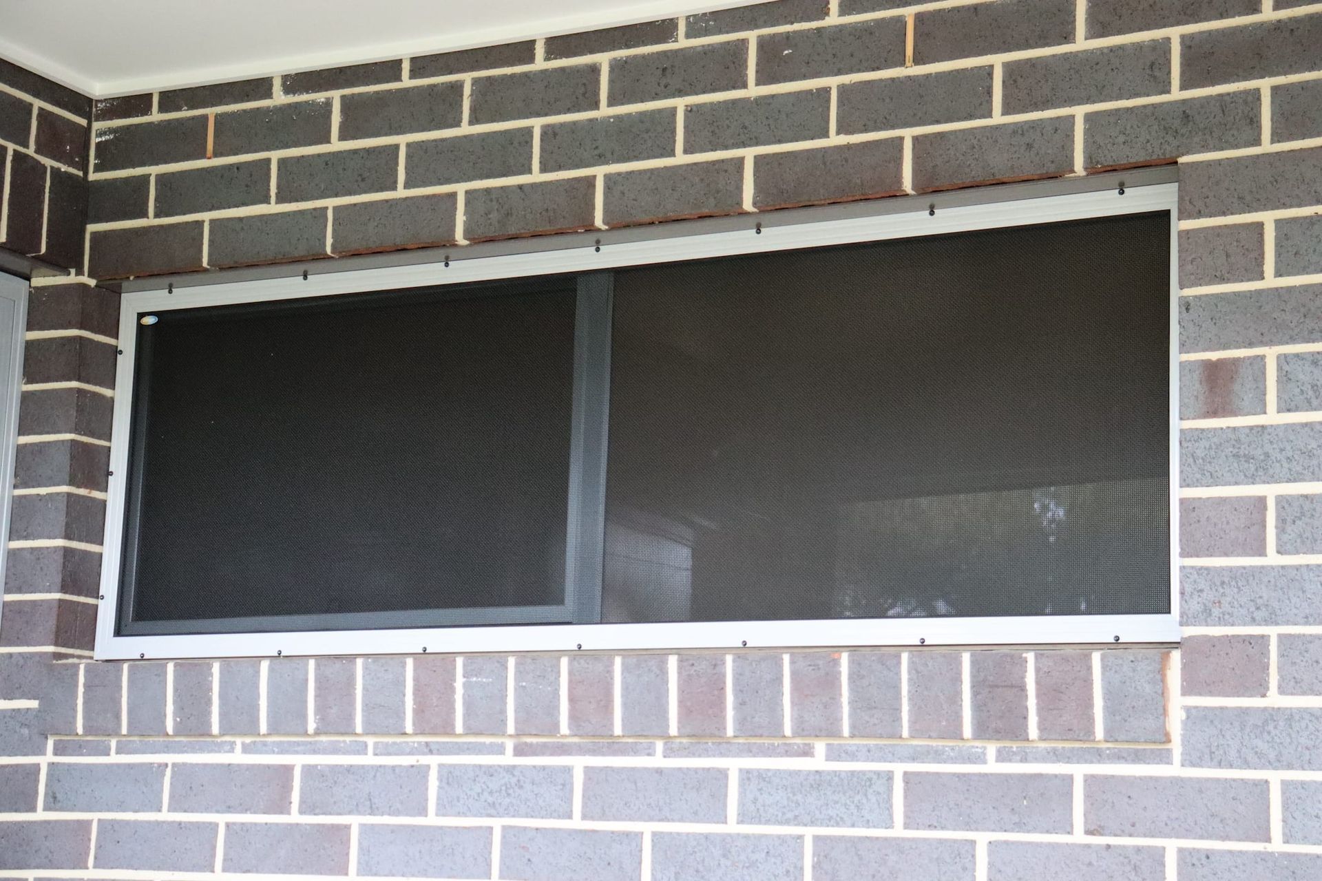 A brick wall with a window with a screen on it