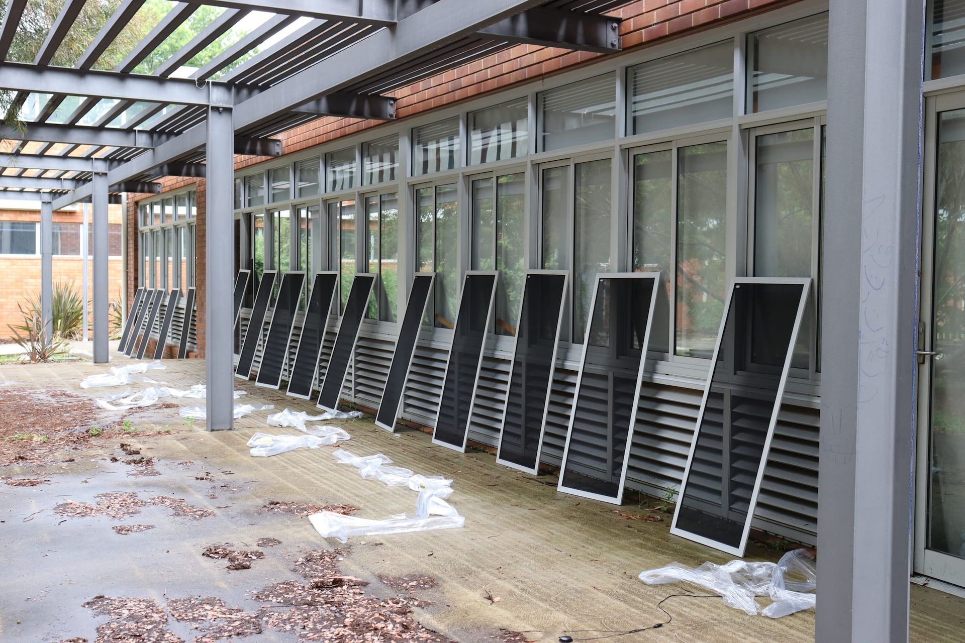 A row of solar panels are lined up in front of a building.