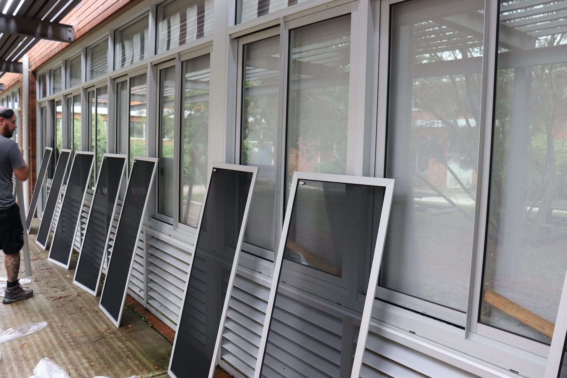 A man is standing in front of a building with a lot of windows.