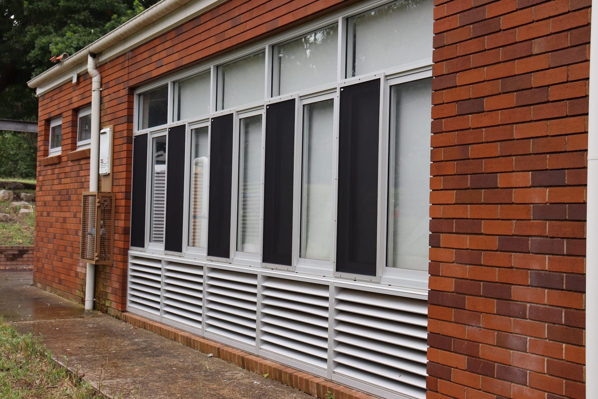 A brick building with a lot of windows and black blinds on the windows.
