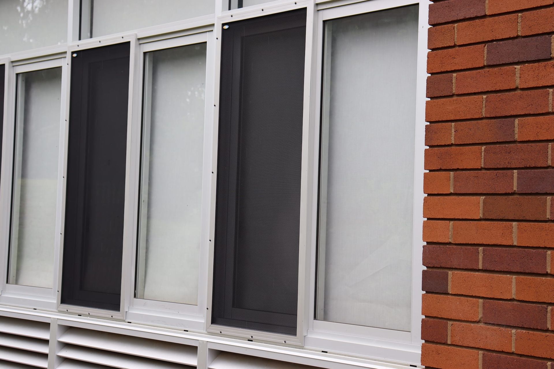 A brick building with a row of windows with screens on them