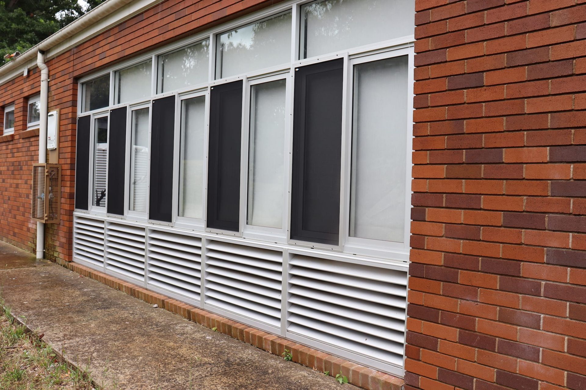 A brick building with a lot of windows and shutters on it.